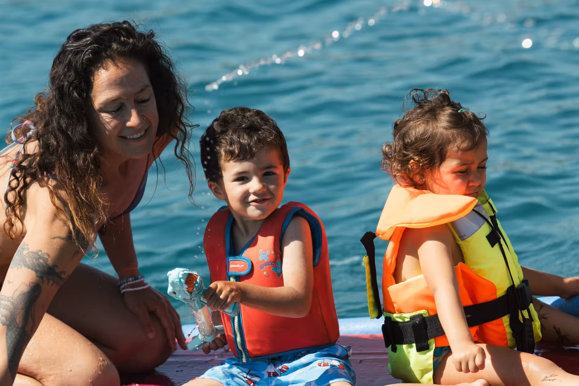 Family enjoying Algarve boat tour with kids wearing life jackets on sparkling blue ocean waters
