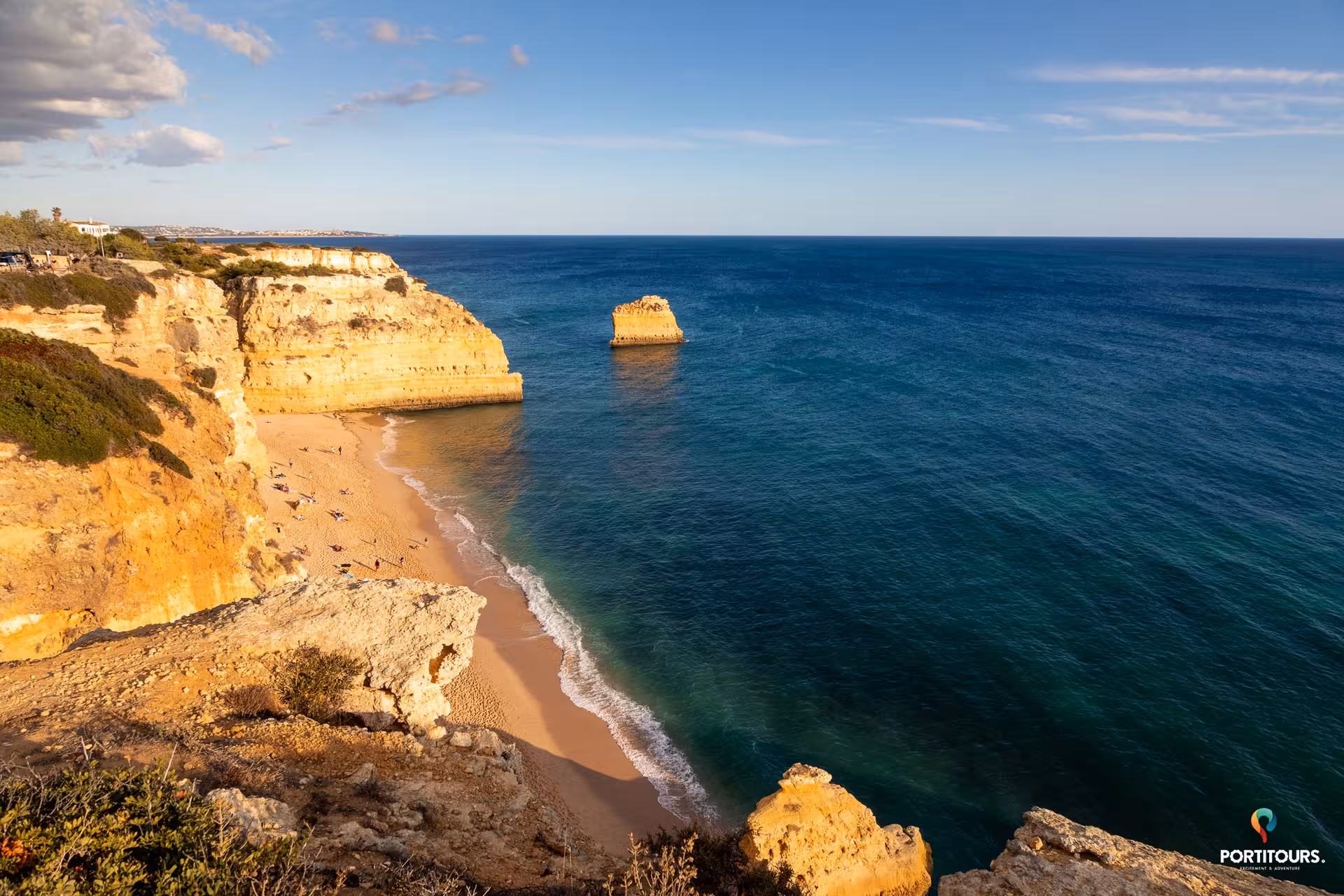 Sweeping view of Algarve golden cliffs and secluded beach on the Atlantic coast, featured on panoramic wine tasting tours