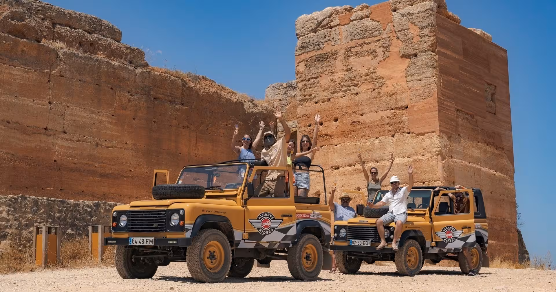 Smiling travelers in open jeeps by ancient Algarve fortress ruins under blue skies on The Algarve Heritage Journey