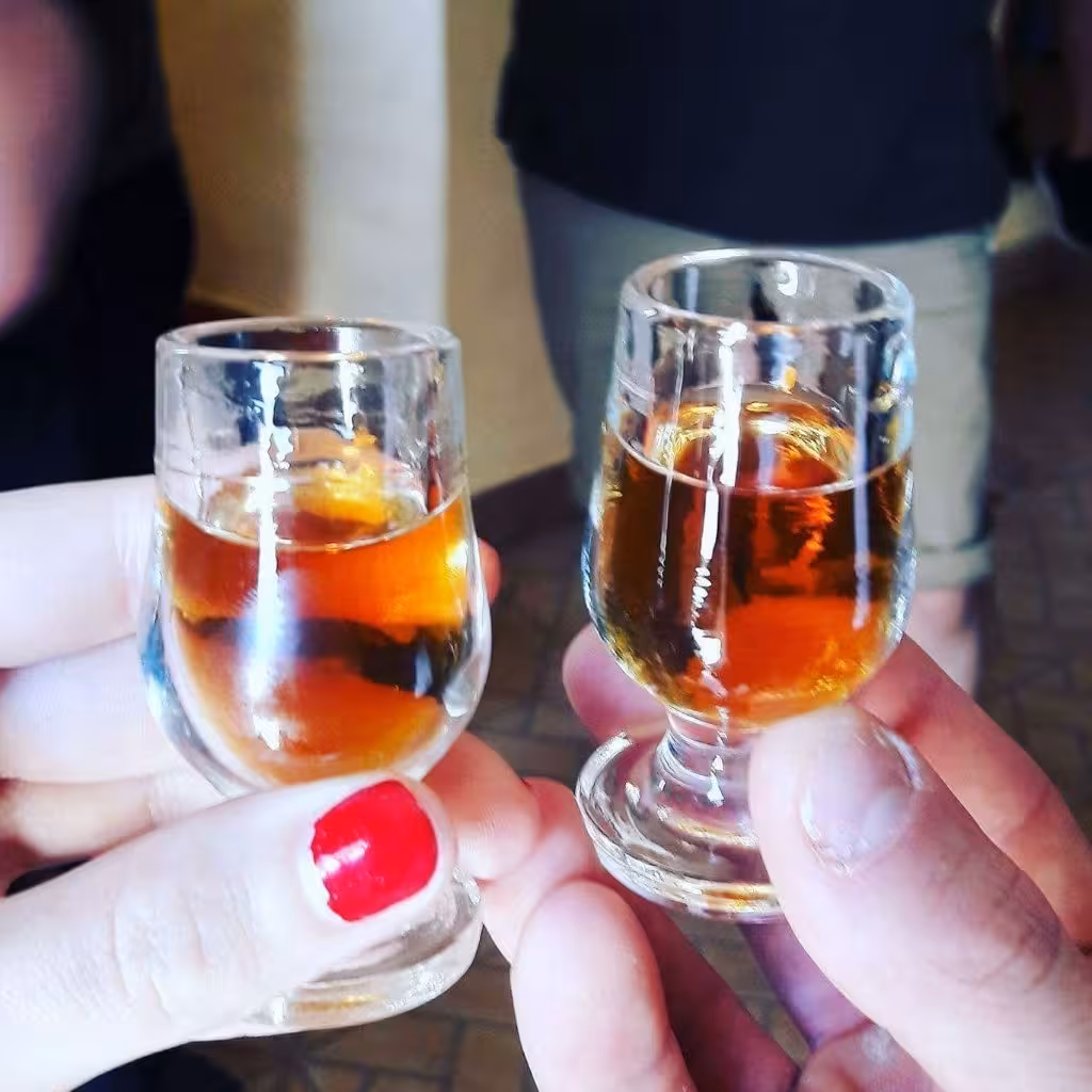 Close-up of two travelers toasting local Algarve liqueur during a traditional tasting stop on a half day jeep safari