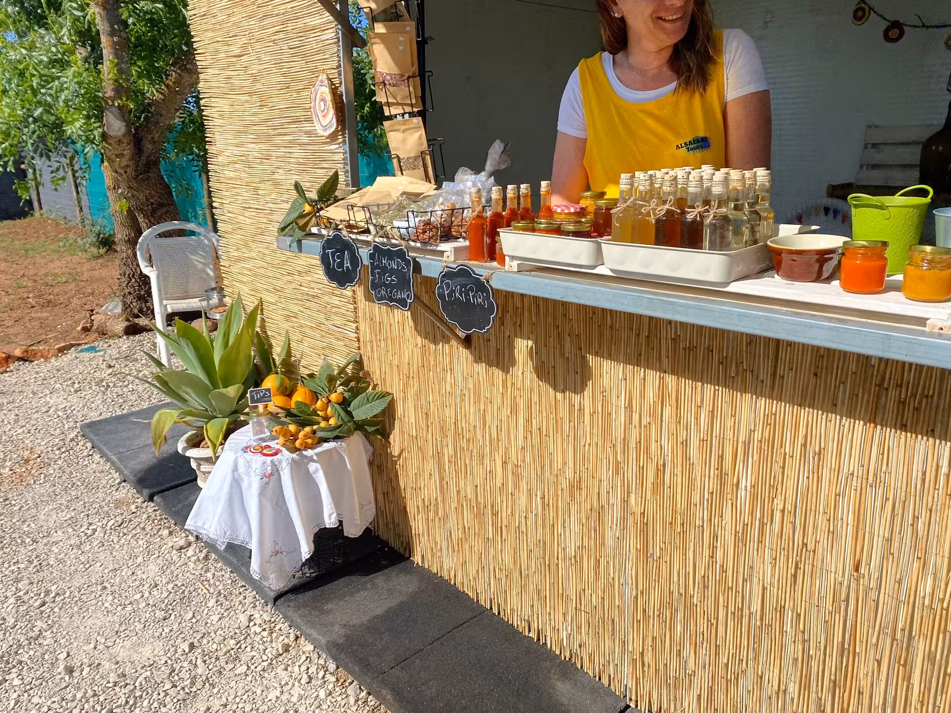 Smiling host at rustic Algarve farm stall selling teas, piri-piri, jams and citrus fruits on a full day Jeep safari lunch tour