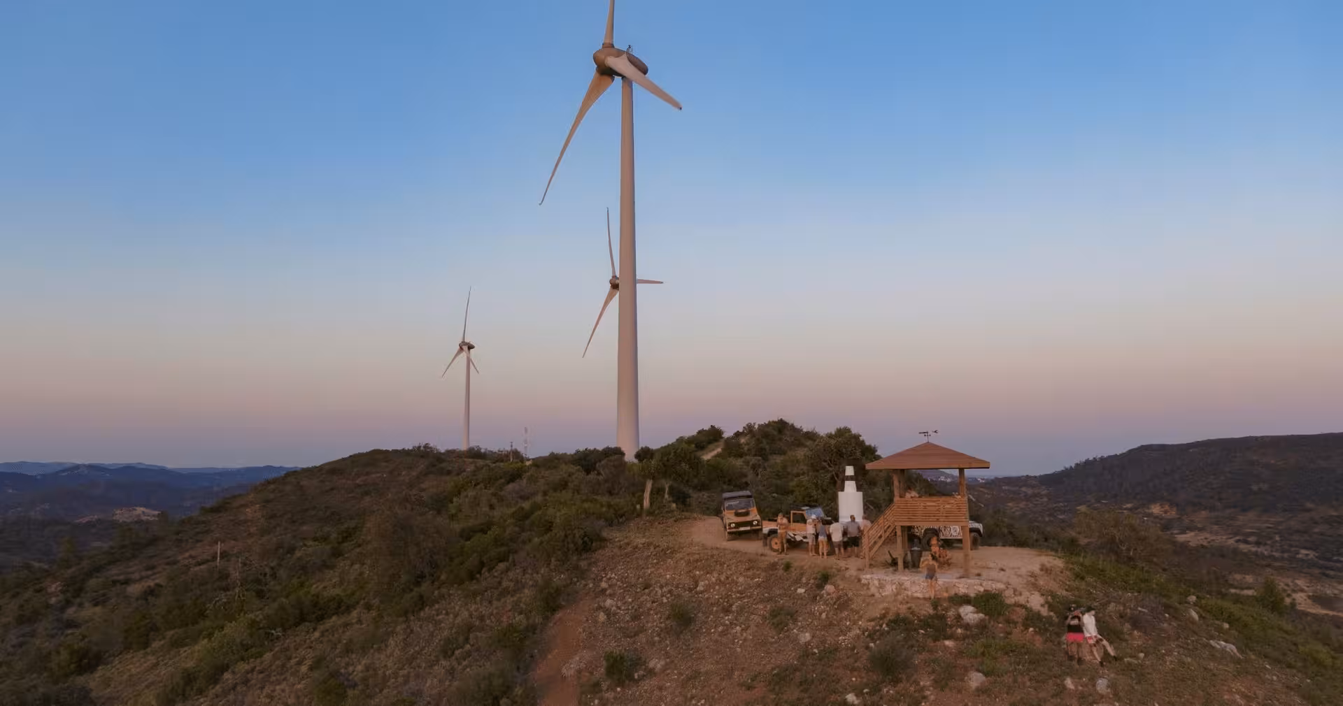 Aerial view of jeep safari group at Algarve hilltop wind farm during a stunning dusk private tour