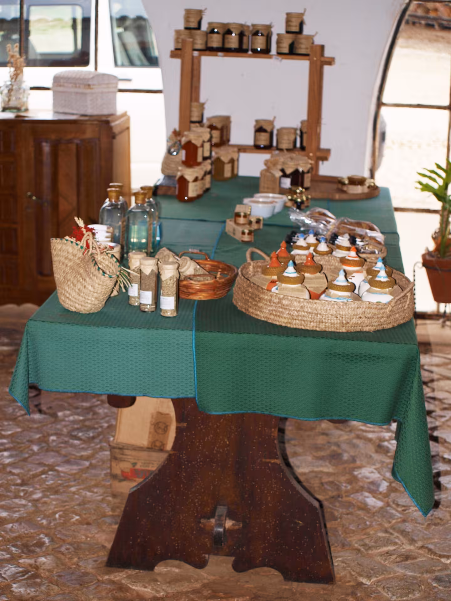 Rustic Algarve farm shop table displaying local honey, preserves, olive oil and crafts on a green cloth for tasting
