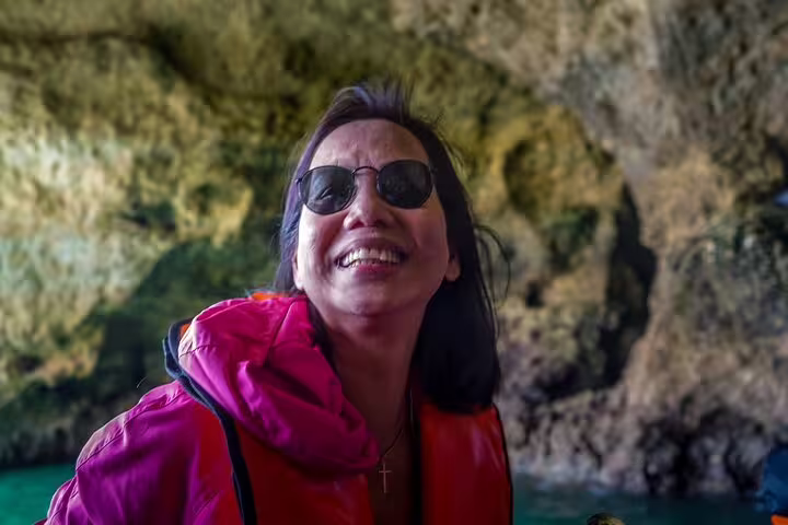 Smiling tourist enjoys the Algarve private tour from Lisbon, exploring the stunning Benagil Caves on a scenic boat trip.