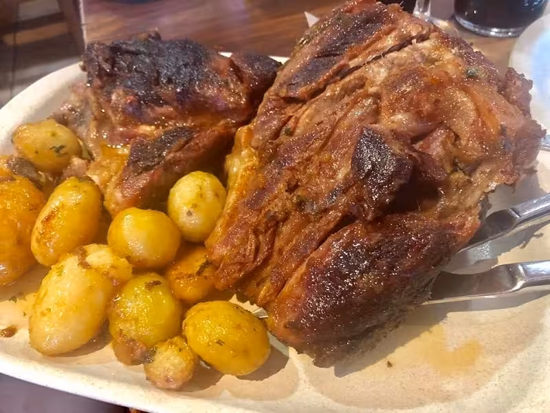 Roasted pork knuckle with golden baby potatoes served on a sharing platter during an Algarve à la Carte food experience