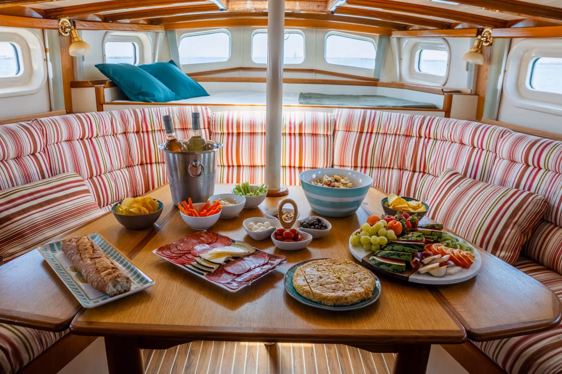 Algarve sailing boat tour lunch spread with charcuterie, fresh fruit, bread, and chilled wine on cabin table