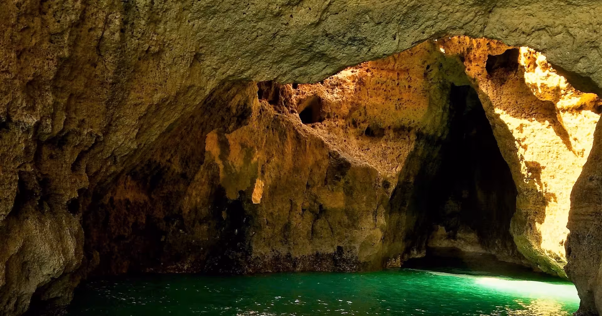 Golden rock arches and emerald water inside a secluded Algarve-style sea cave on the Seasiren 3H tour