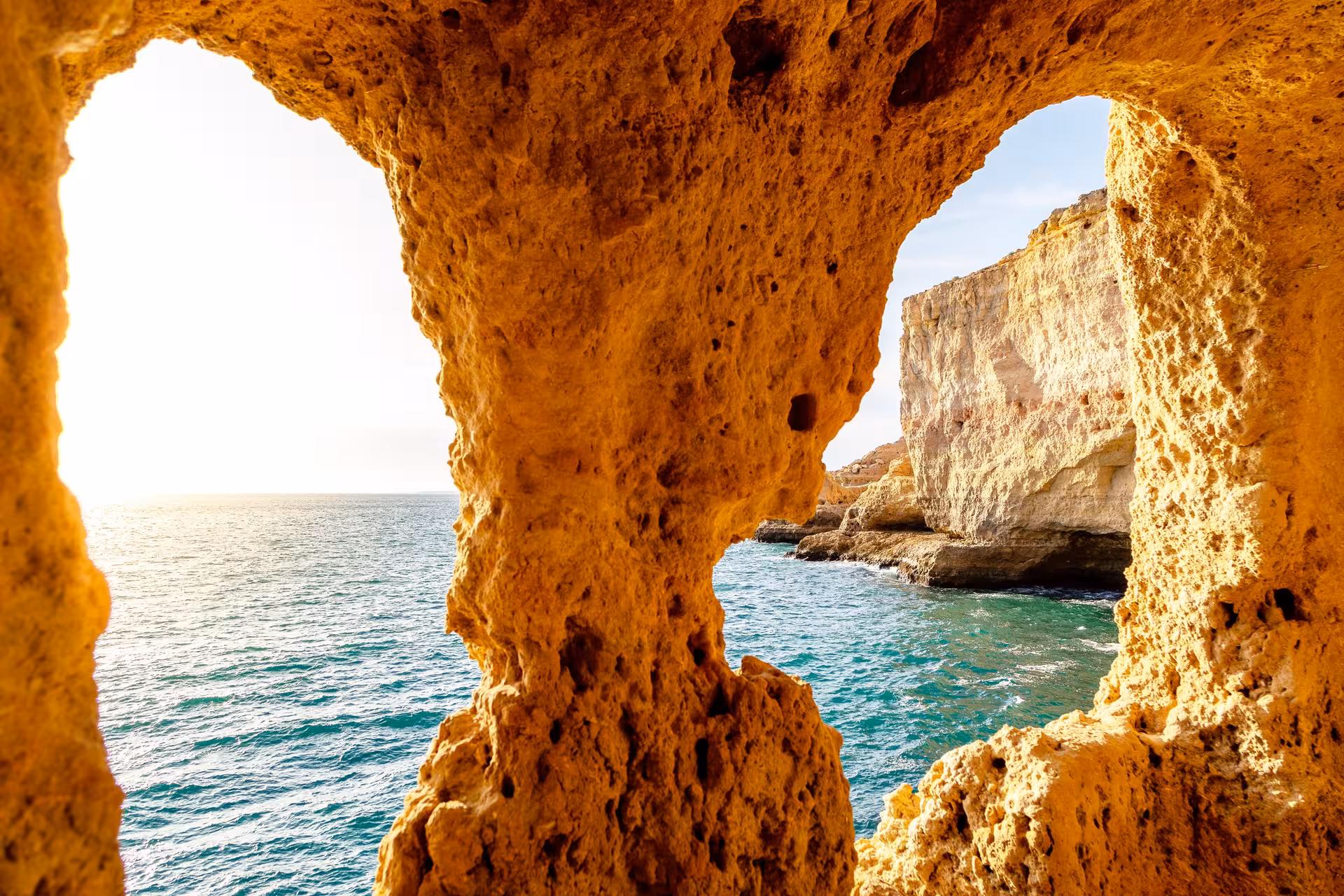 Golden Algarve sea cave framing turquoise Atlantic Ocean views, a scenic highlight of panoramic coastal wine tours