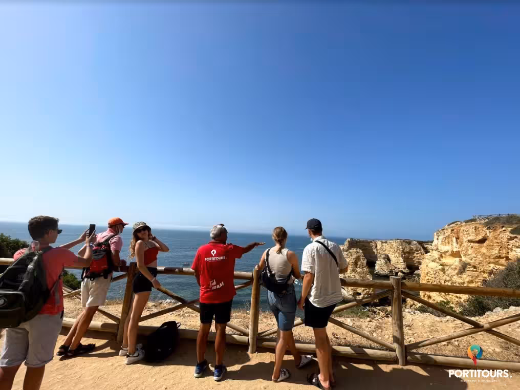Guided group admiring panoramic Algarve sea cliffs on a sunny coastal viewpoint during a scenic wine tasting tour in Portugal