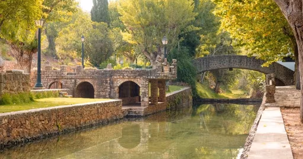 Shaded stone canal and arched bridge in a tranquil Algarve hill village, a peaceful stop on The Hills & Traditions Trail