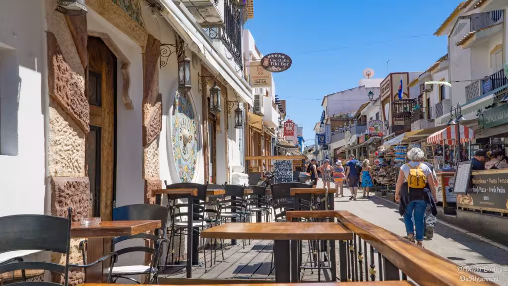 Lively Algarve street with outdoor cafés, local shops and visitors exploring on Landscapes and Traditions walking tour