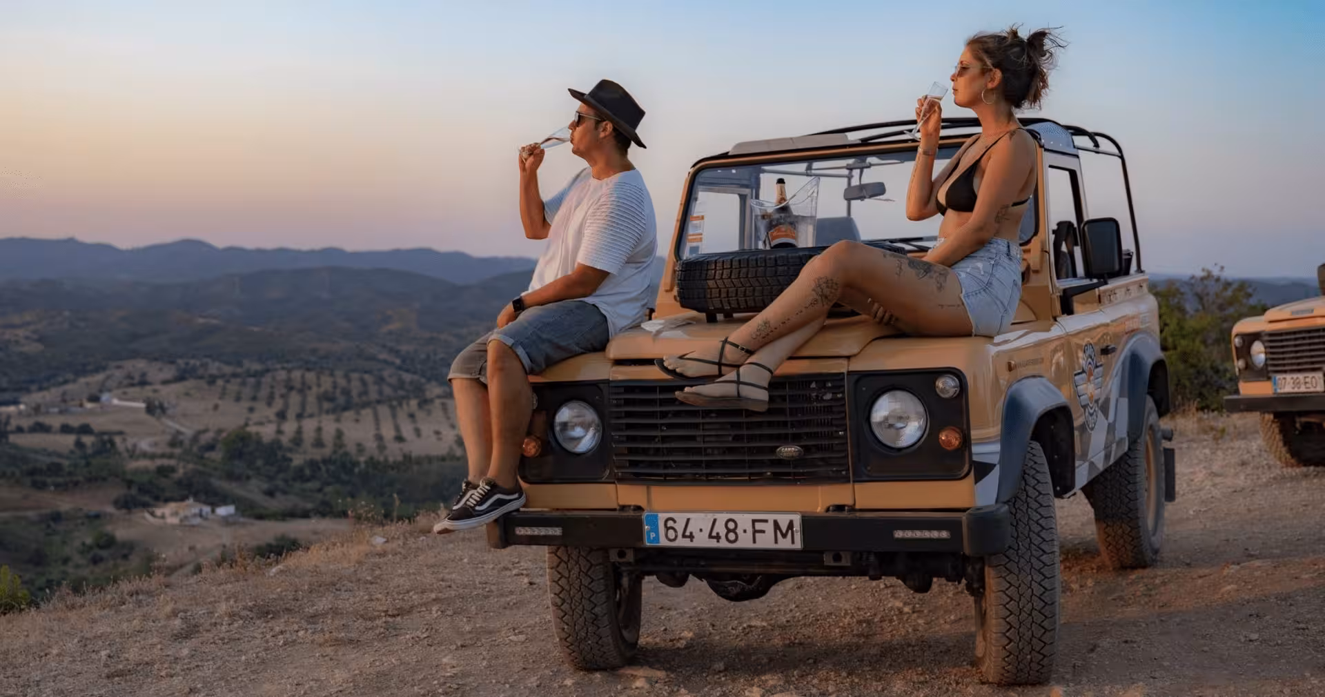 Couple sipping champagne on a vintage jeep hood during a private Algarve sunset safari tour