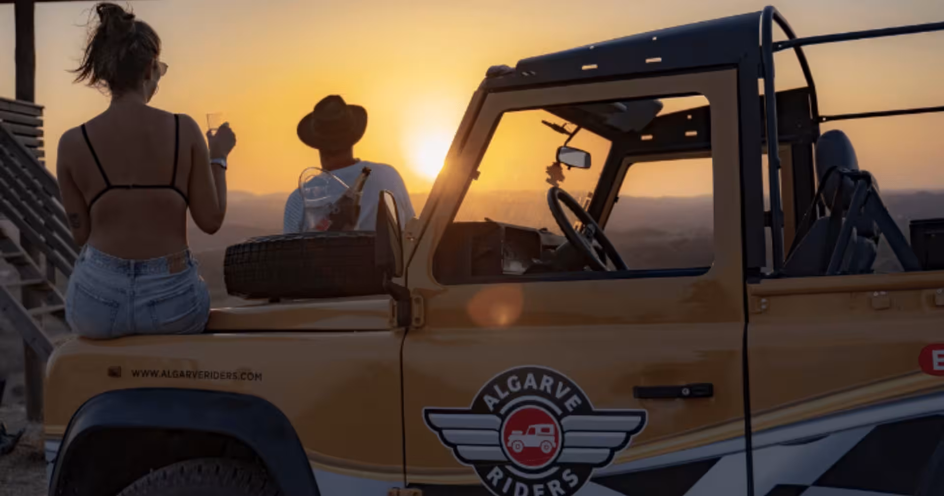 Couple sipping champagne beside an Algarve Riders jeep enjoying a stunning golden sunset private safari tour