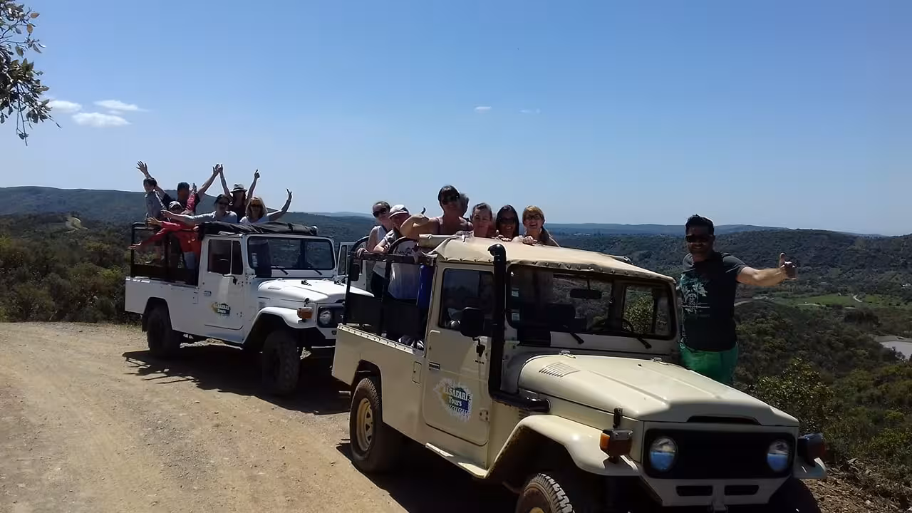 Group celebrating Algarve sunset jeep safari on hilltop viewpoint, raising sparkling wine flutes above scenic countryside