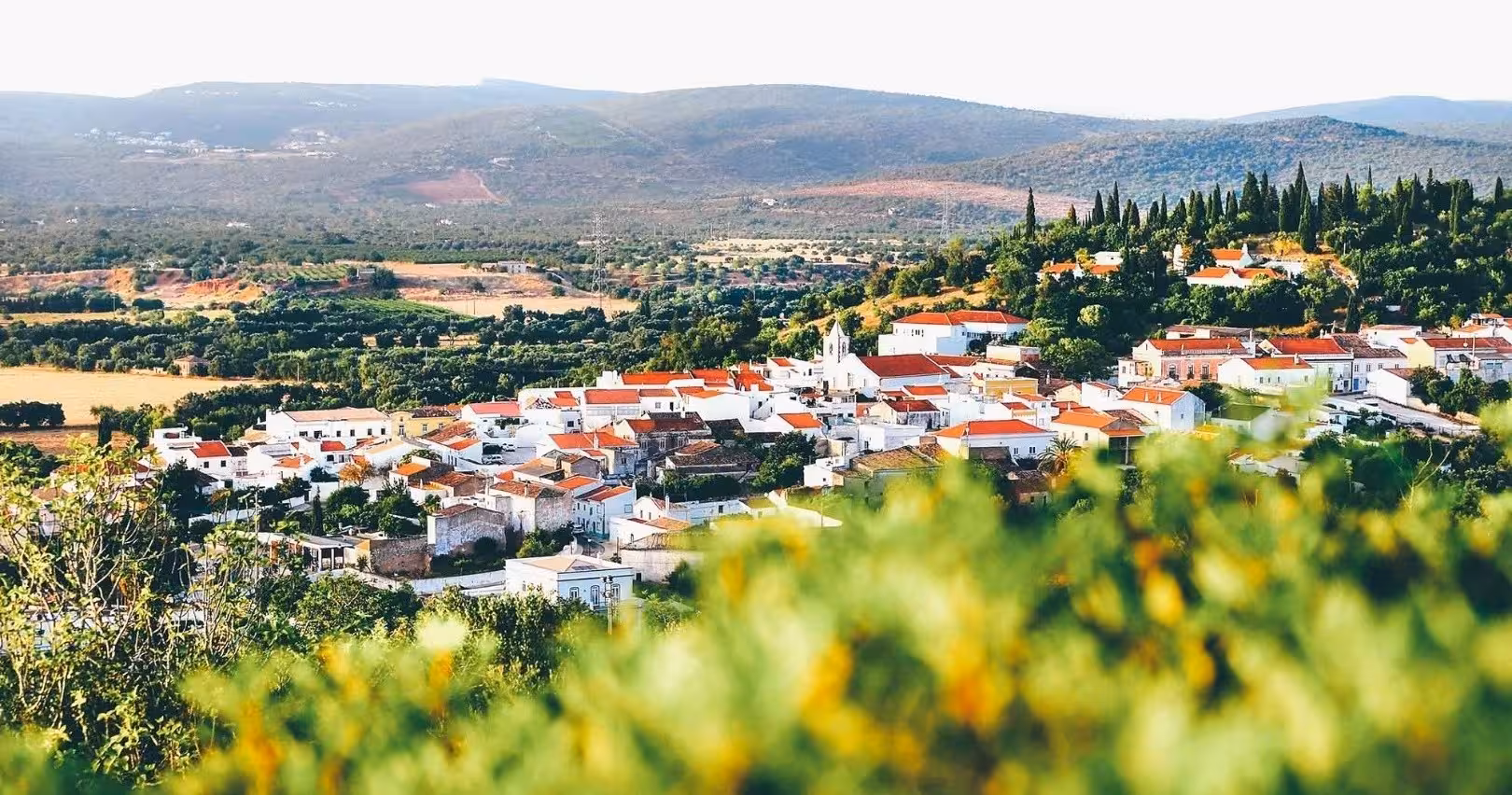 Panoramic view of a whitewashed Algarve village with red roofs, rolling green hills and vineyards on a Spirit & Springs tour