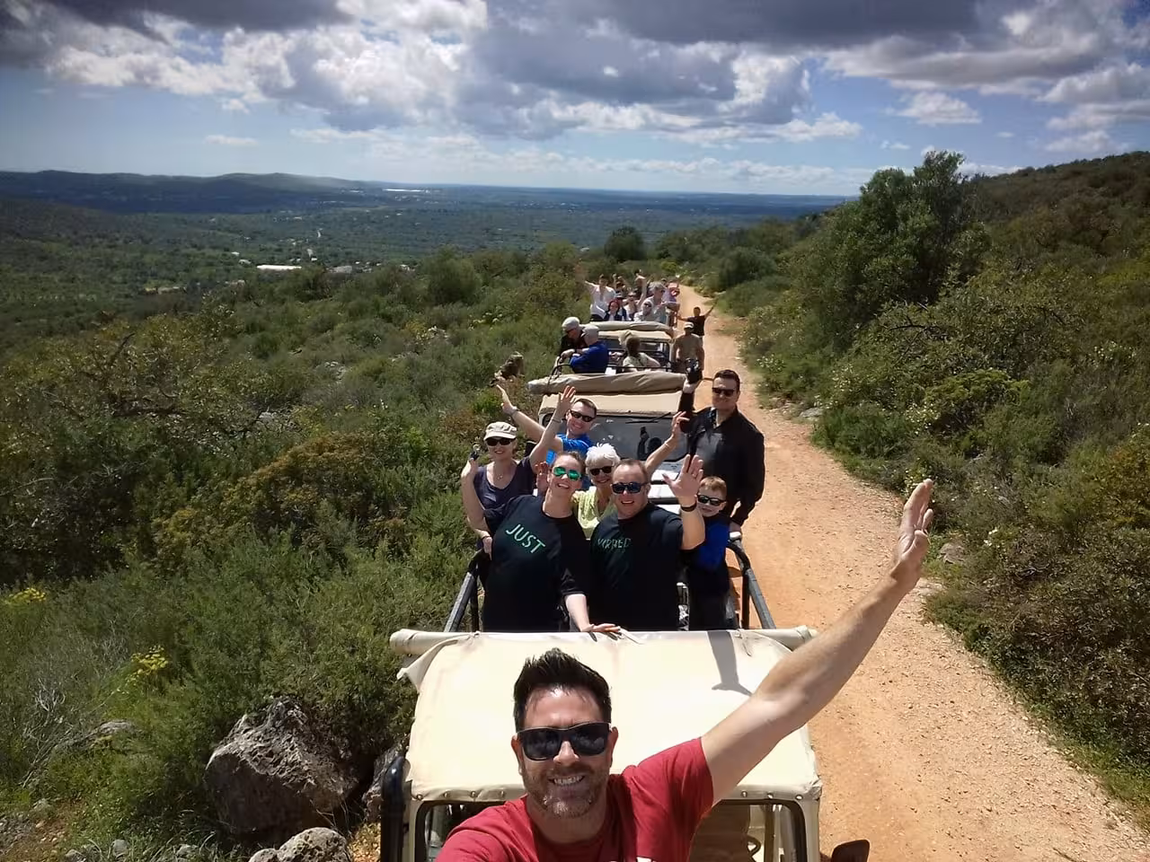 Happy group on open-top jeeps driving a scenic dirt road through Algarve vineyards on a half day wine tasting tour