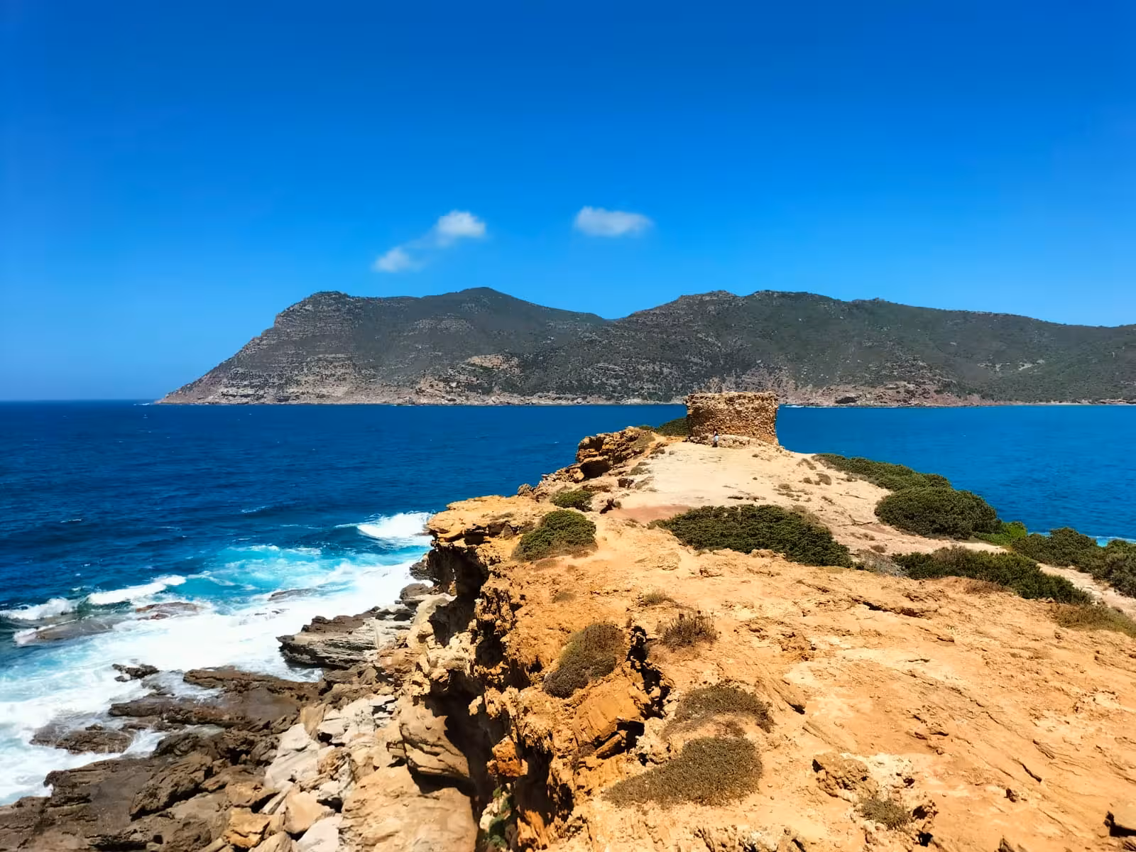 Dramatic cliffs and azure waves at Argentiera, showcasing rugged coastlines on the off-road tour from Alghero.
