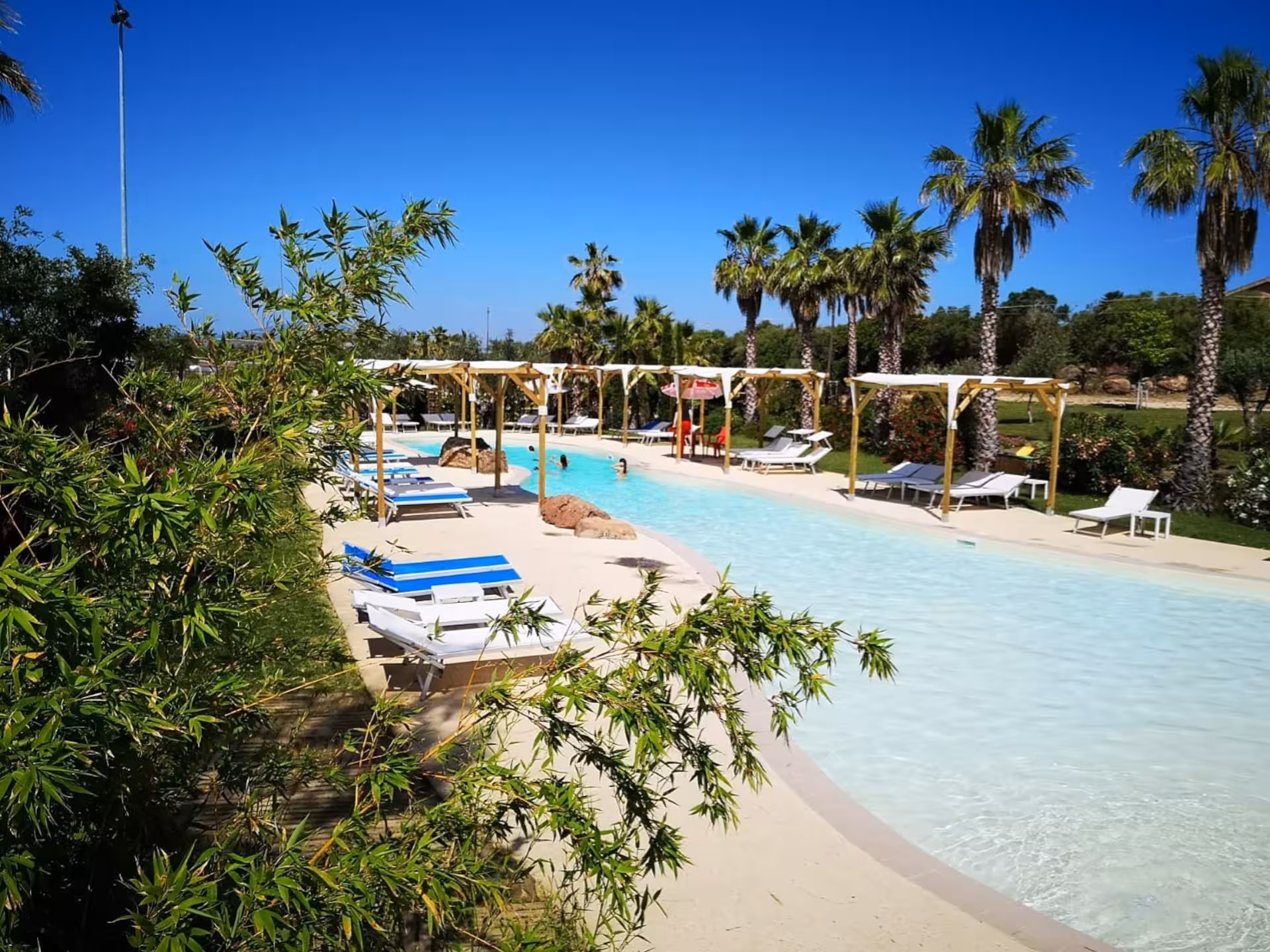 Relax by the serene pool surrounded by lush greenery and palm trees at Alghero Butterfly House tour.
