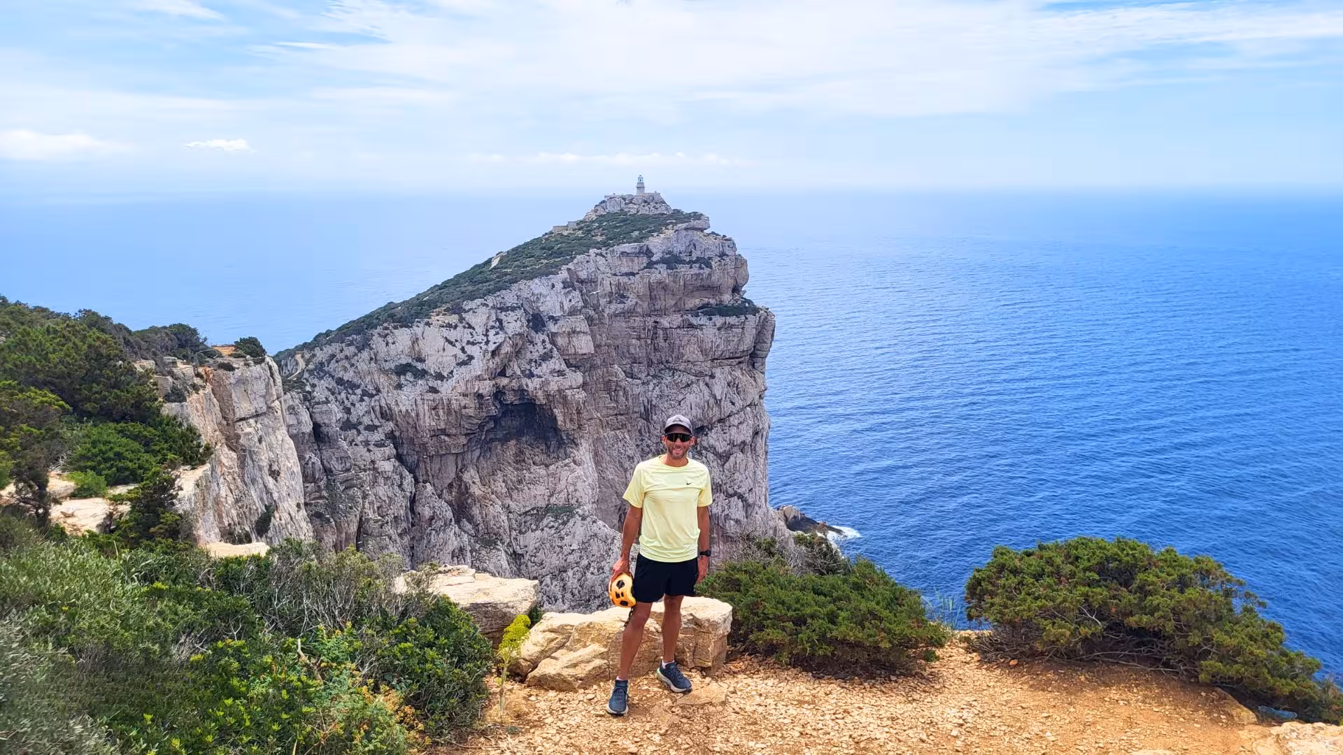 Man stands at a picturesque viewpoint on Capo Caccia, Alghero, with expansive sea and cliff views during an ebike tour.