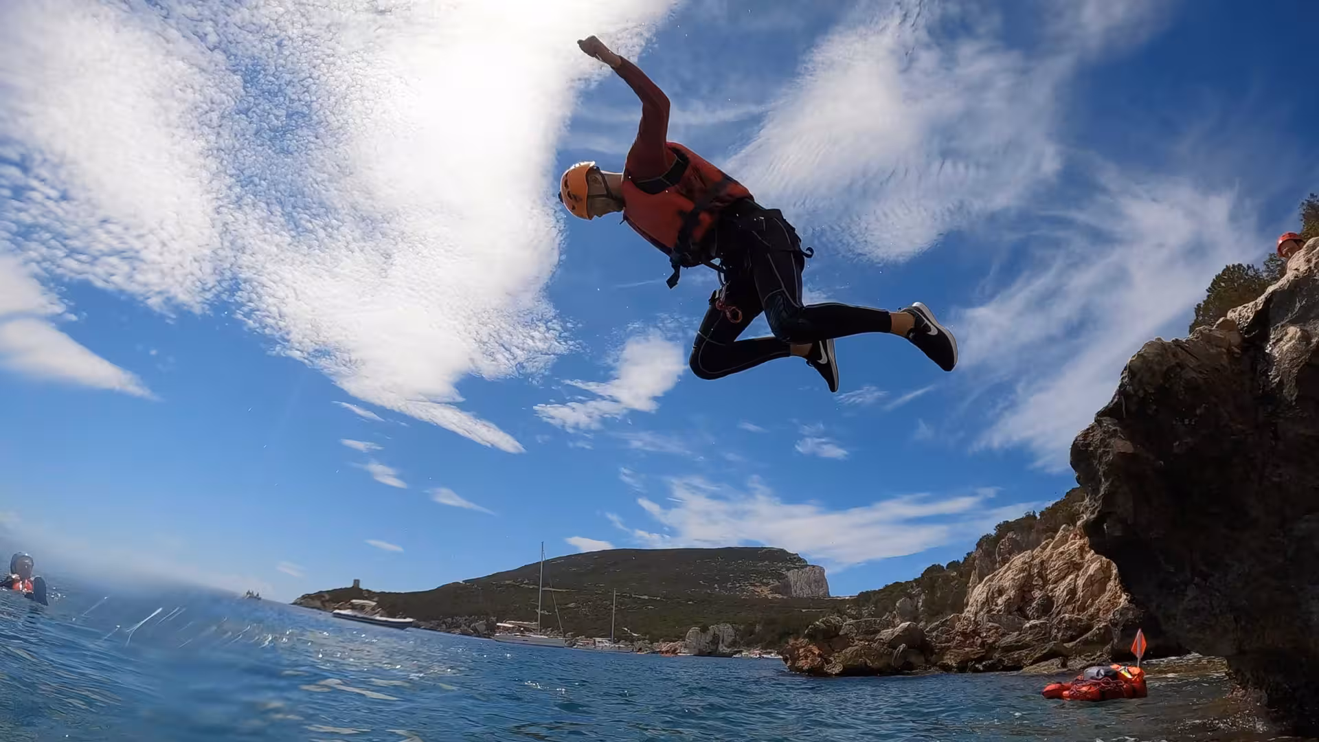 Thrilling cliff jump at Porto Conte Park with a clear blue sky, showcasing coasteering adventure in Alghero.