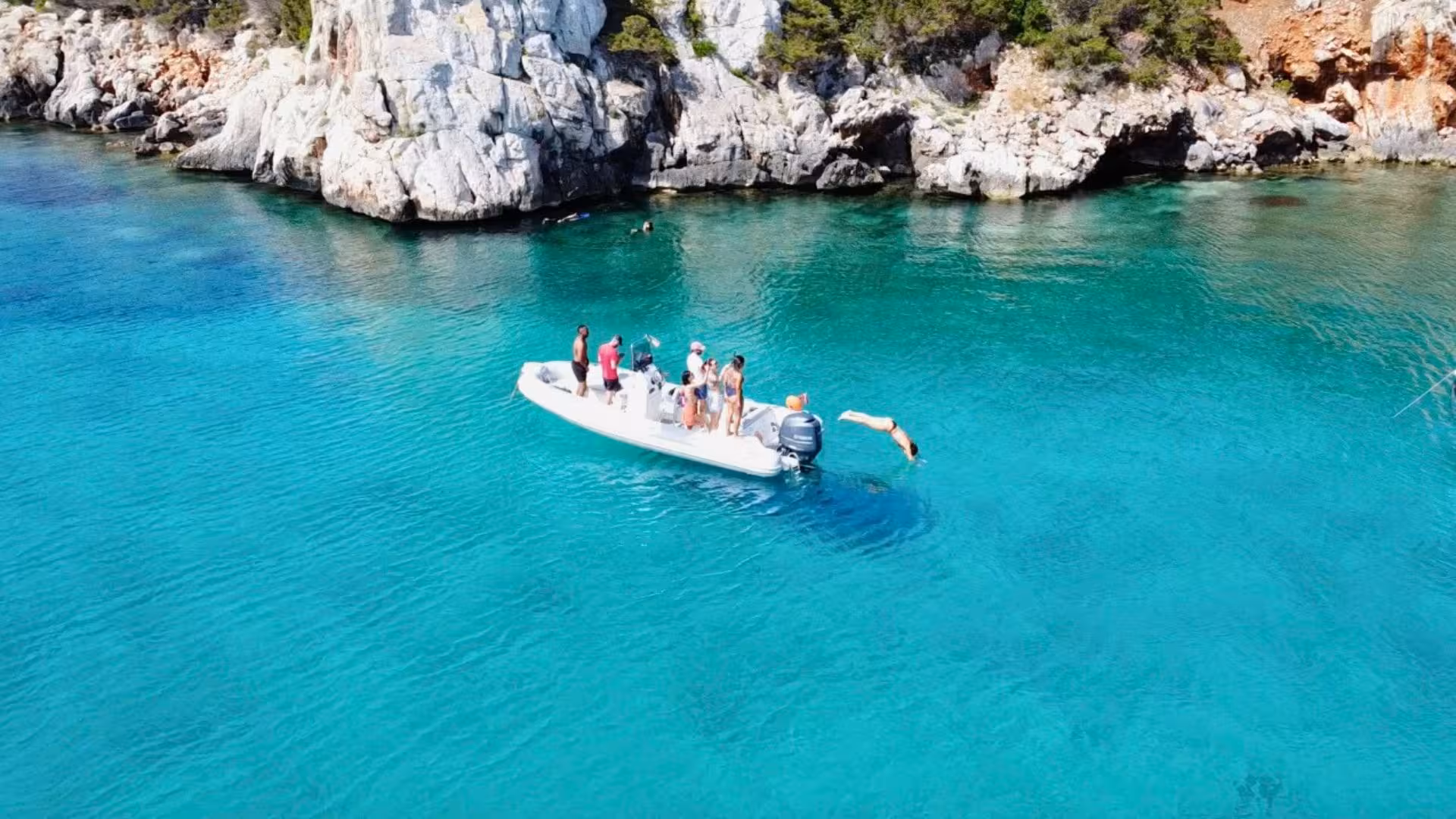 Group of tourists enjoying a snorkeling tour from a dinghy near the cliffs of Capo Caccia, Alghero.