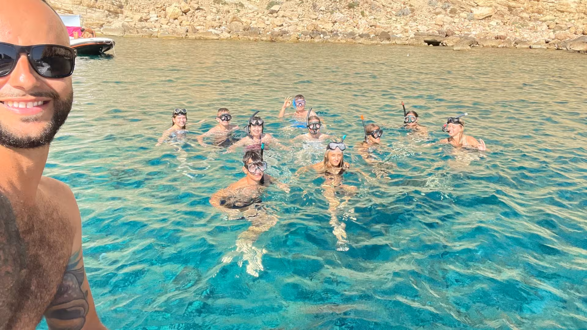Group of happy snorkelers in Porto Conte's crystal-clear waters enjoying Alghero dinghy tour near Capo Caccia.