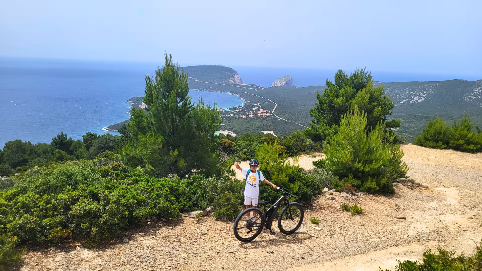 Cyclist enjoying panoramic views of Porto Conte Park and the Mediterranean on an Alghero e-bike tour.