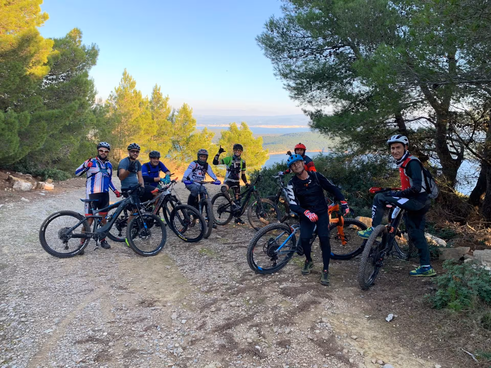 Group of cyclists on an ebike tour through lush Porto Conte Park in Alghero, enjoying panoramic views.