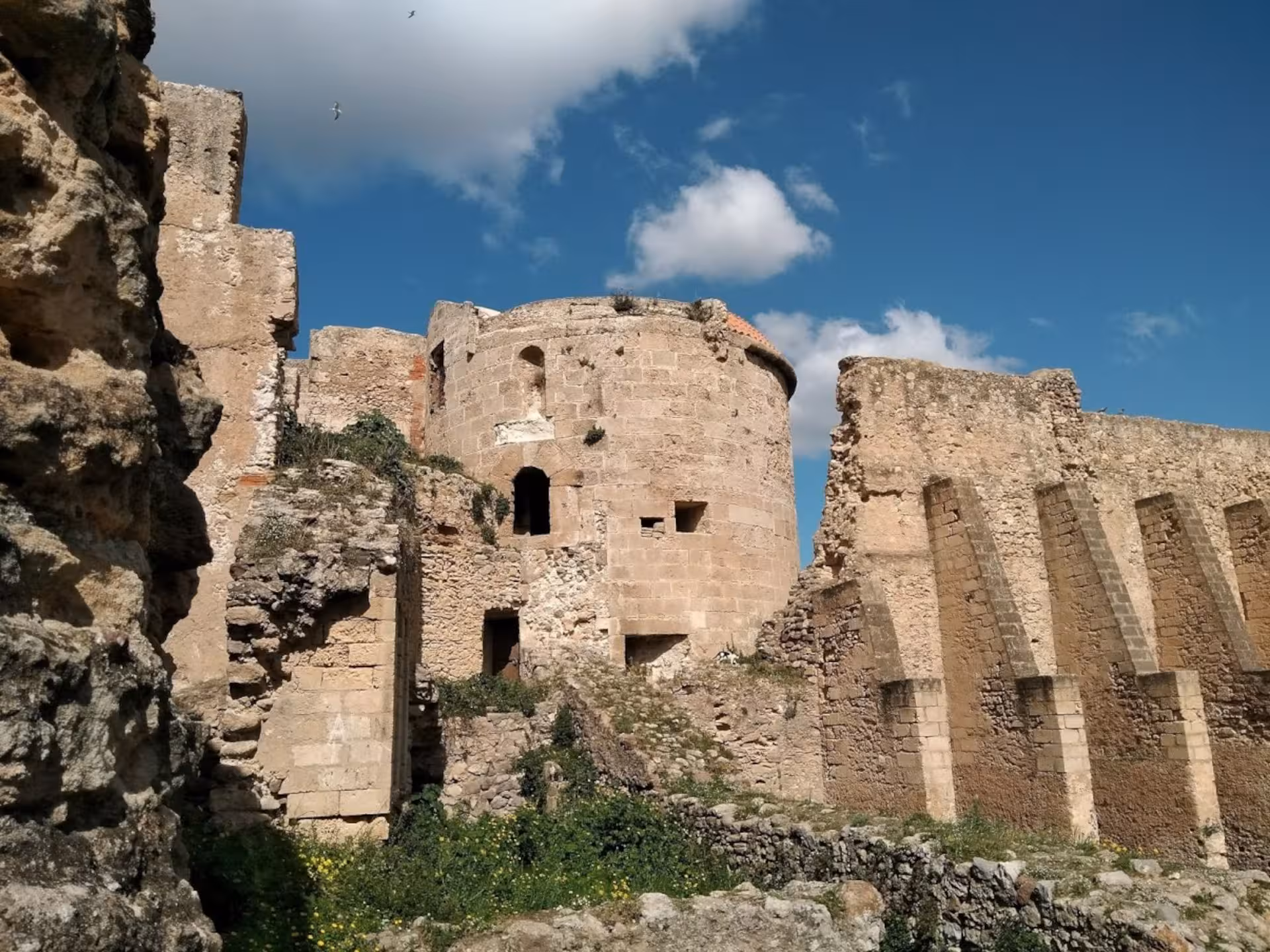 Ancient stone fortress under a bright blue sky in Alghero's historic center, ideal for cultural tours.