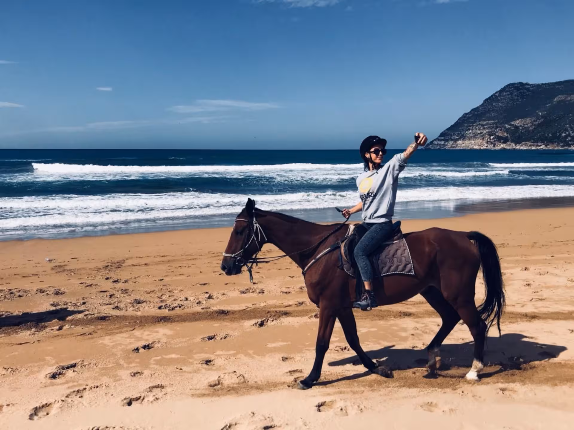 Solo horseback rider enjoying a sunny day on the sandy beaches of Porto Ferro with ocean views in Alghero.