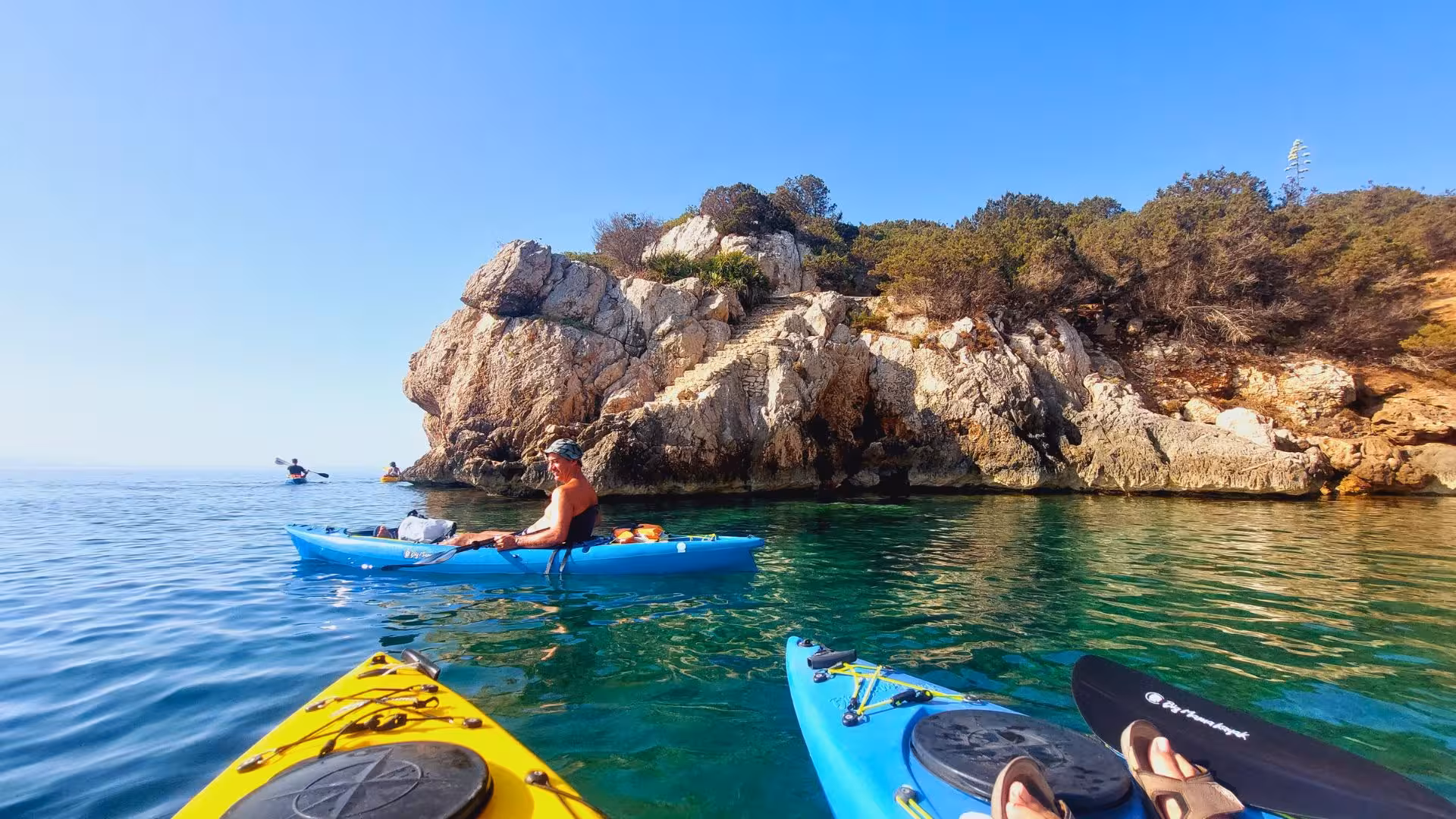 Group of kayakers exploring the rocky coastlines of Porto Conte Park in Alghero during a guided kayak tour.