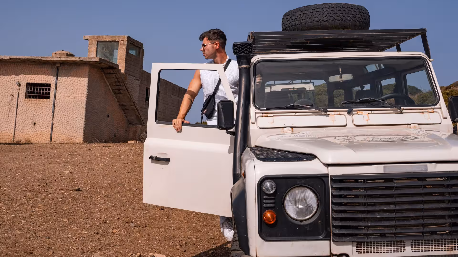 Tourist exiting an off-road vehicle in a rugged landscape near Argentiera during an Alghero adventure tour.