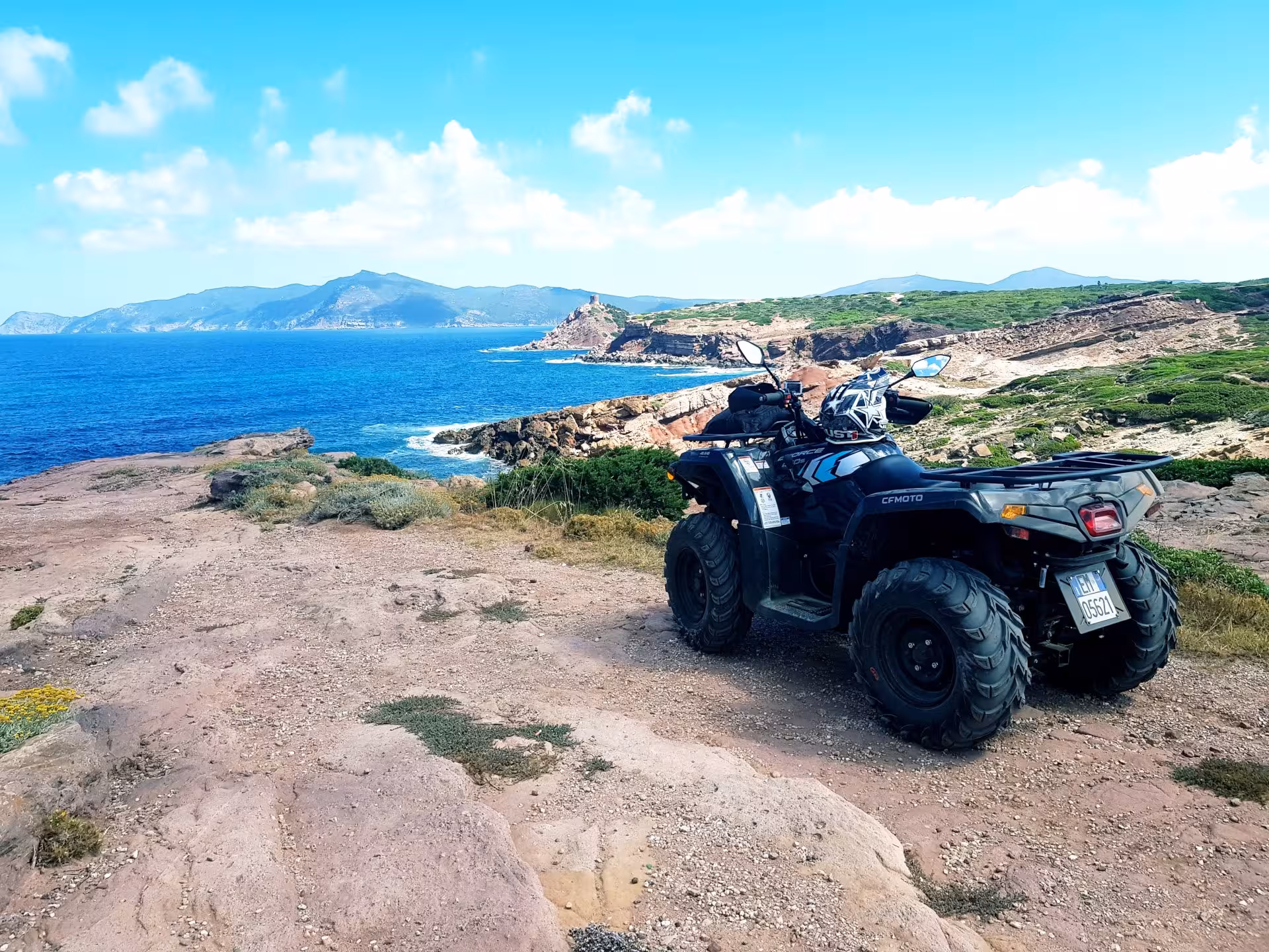 Quad bike parked on a rocky coast with stunning sea views during Alghero's adventurous 4-hour quad tour.