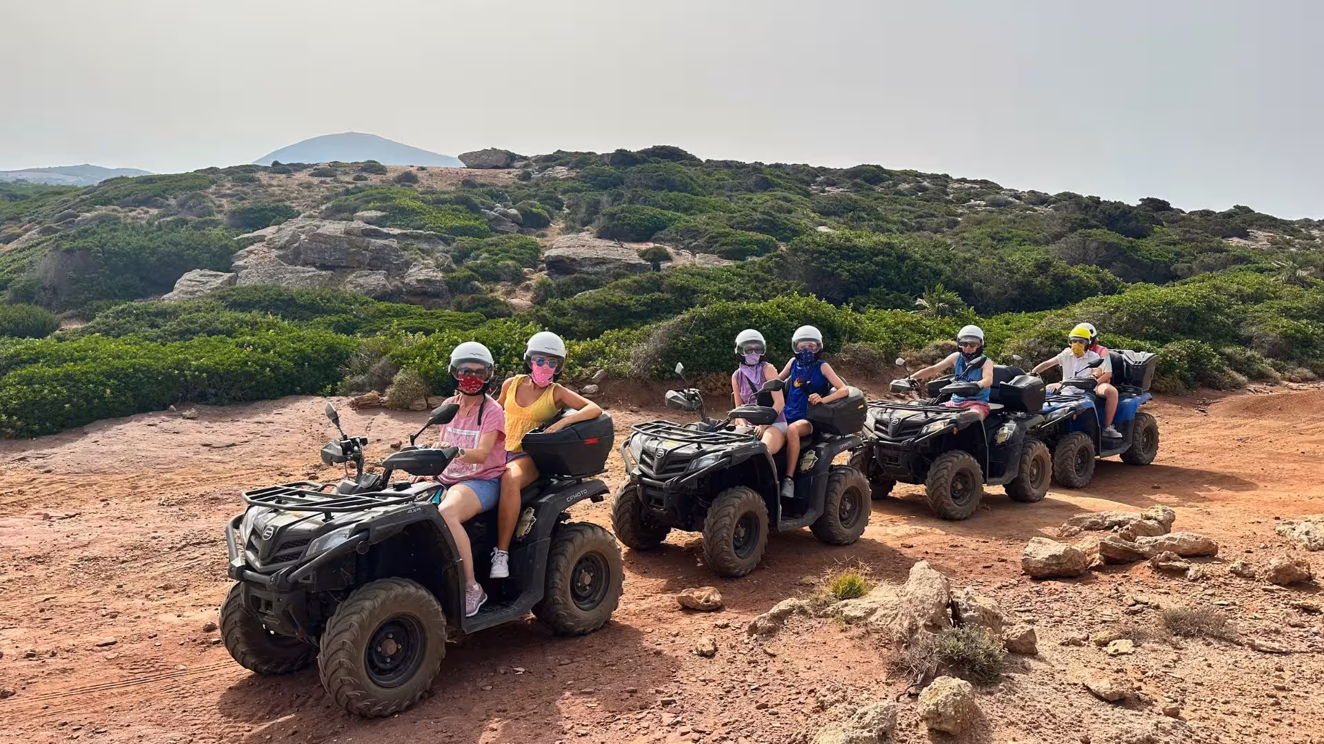 Group of people enjoying an exciting quad tour on rugged terrain in Alghero, surrounded by lush greenery and rocky paths.