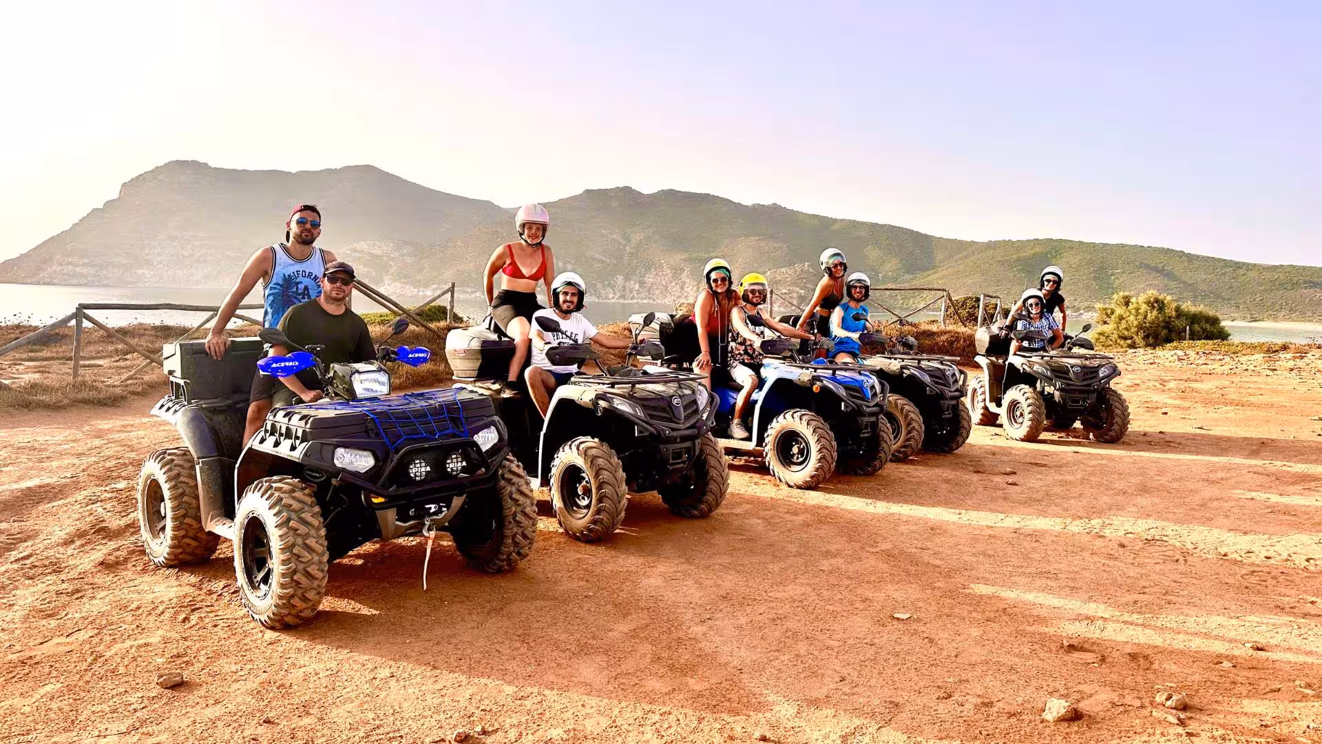 Group enjoying an adventurous Alghero quad tour, set against the stunning backdrop of Sardinia's rugged landscape.