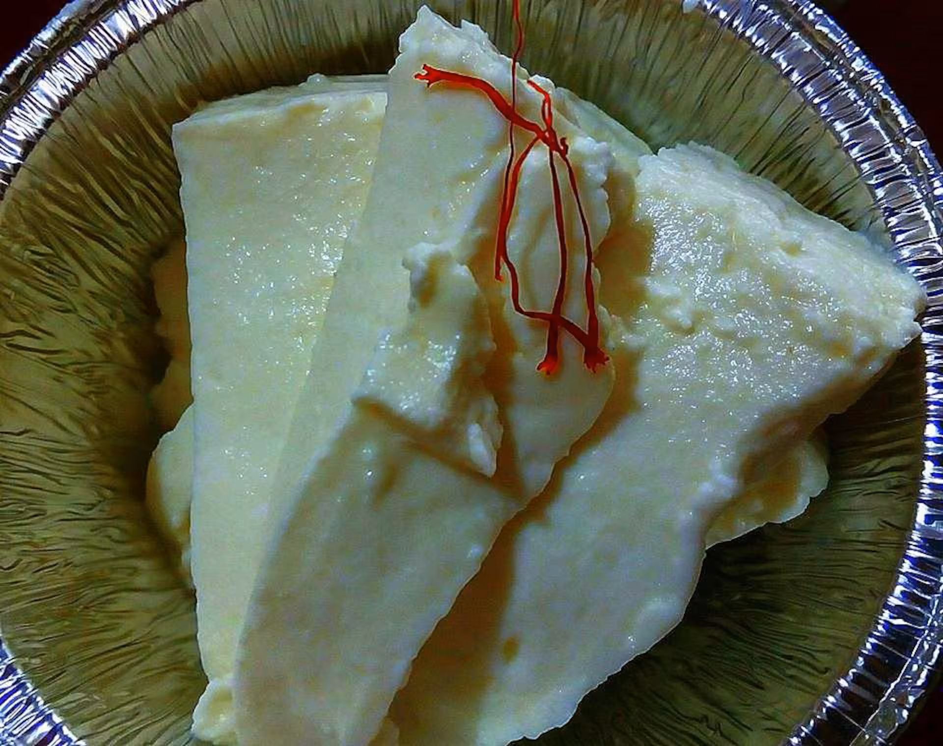 Close-up of creamy cheese garnished with vibrant saffron strands, showcasing the flavors of Olmedo's culinary traditions.