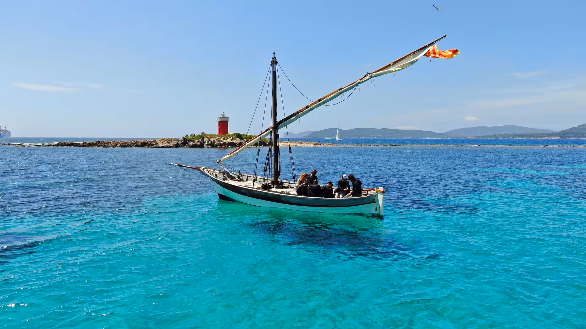 Sailboat gliding over crystal-clear waters near Alghero with a distant lighthouse, ideal for a 4-hour sailing tour.