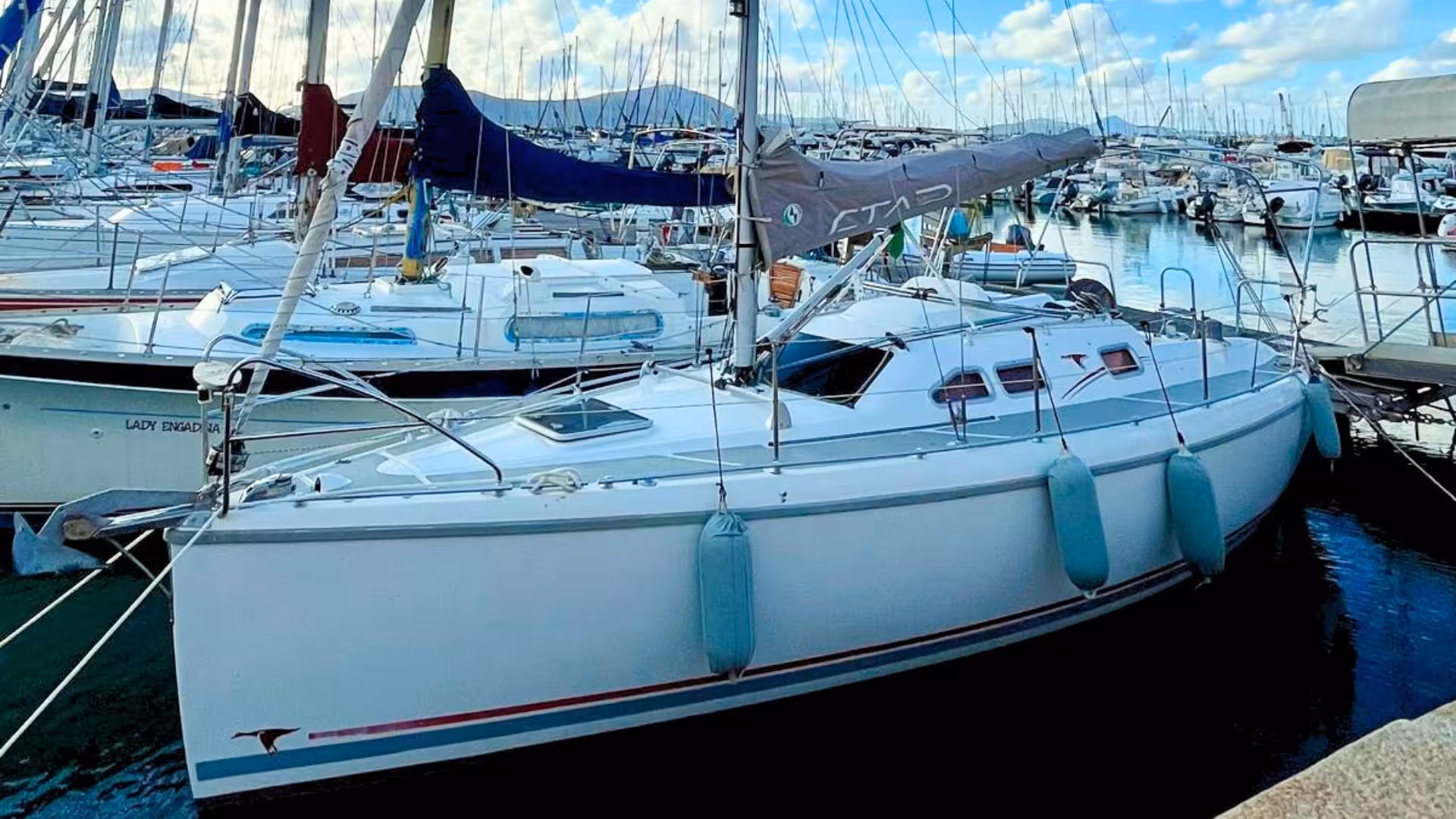 A sleek white sailing boat docked at Alghero marina, ready for an exciting Mediterranean sea tour.