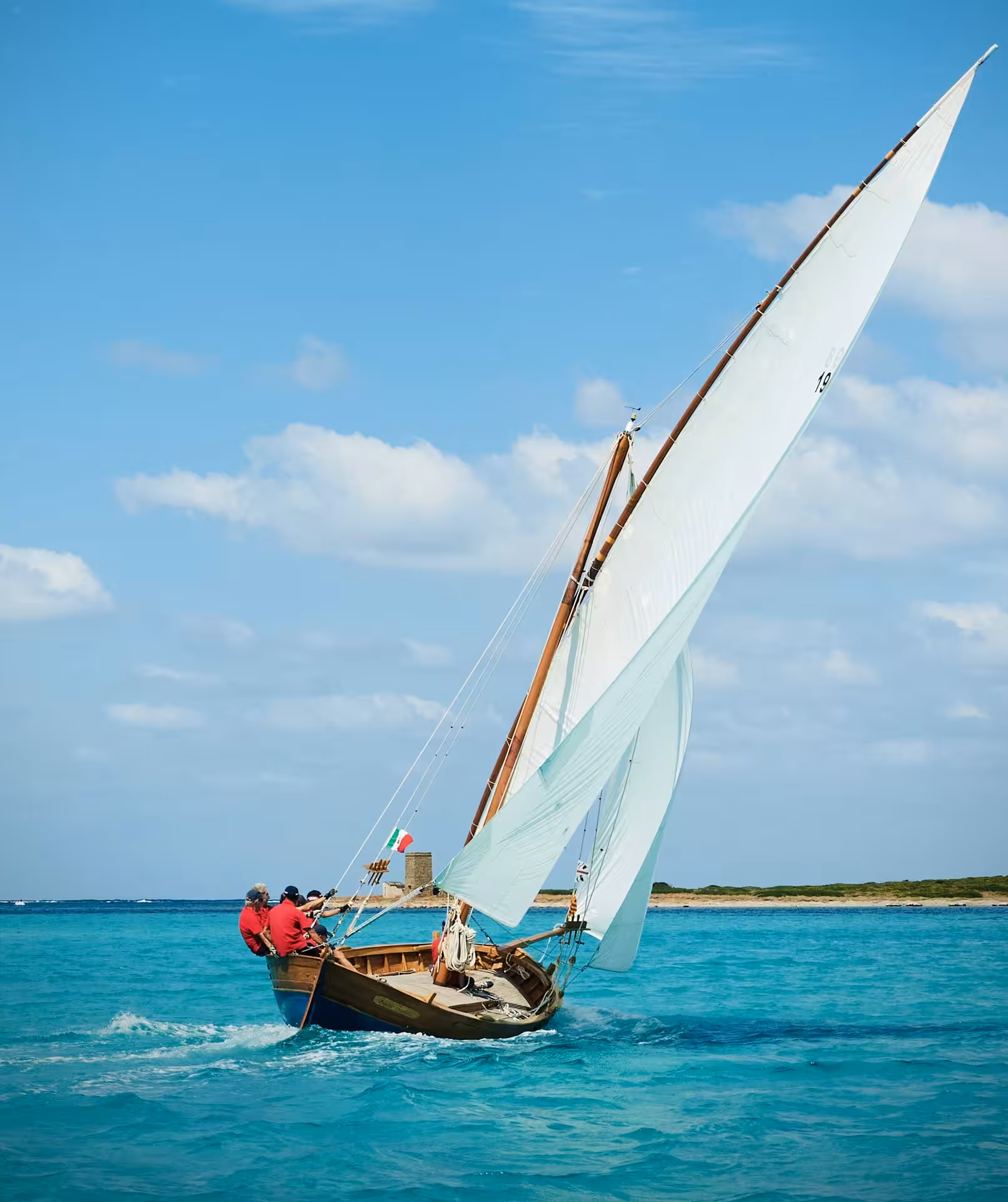 Experience a traditional sailing boat gliding through turquoise waters on a 4-hour tour from Alghero.