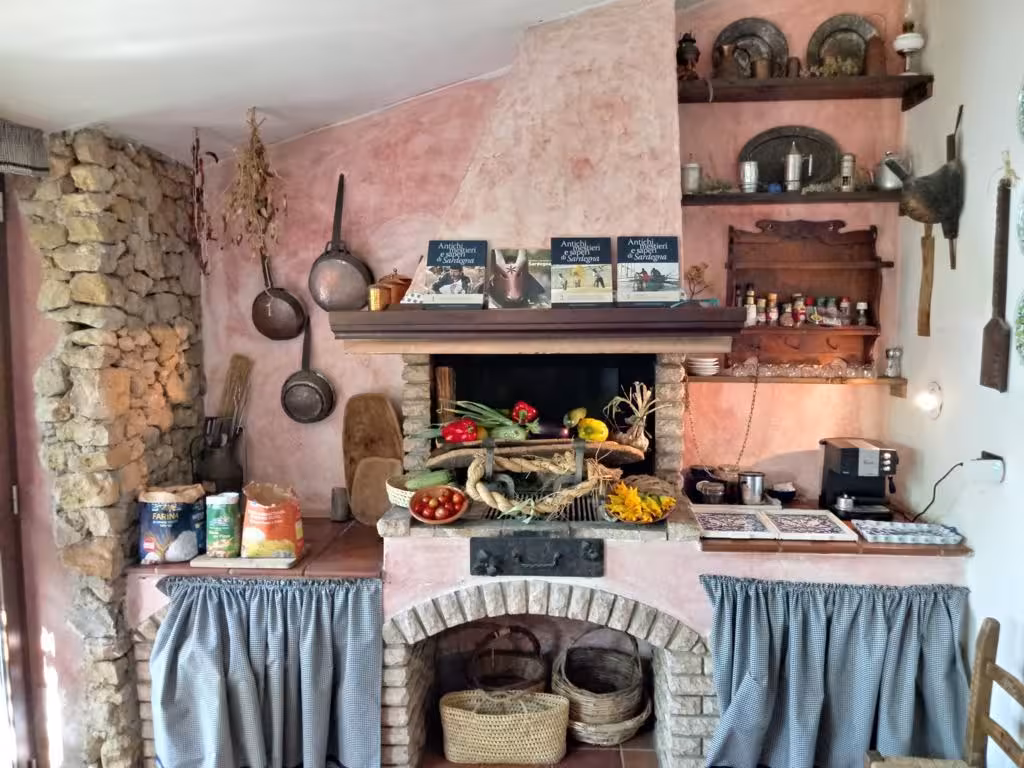 Rustic kitchen interior in Alghero cooking class, showcasing traditional Sardinian cookware and ingredients.