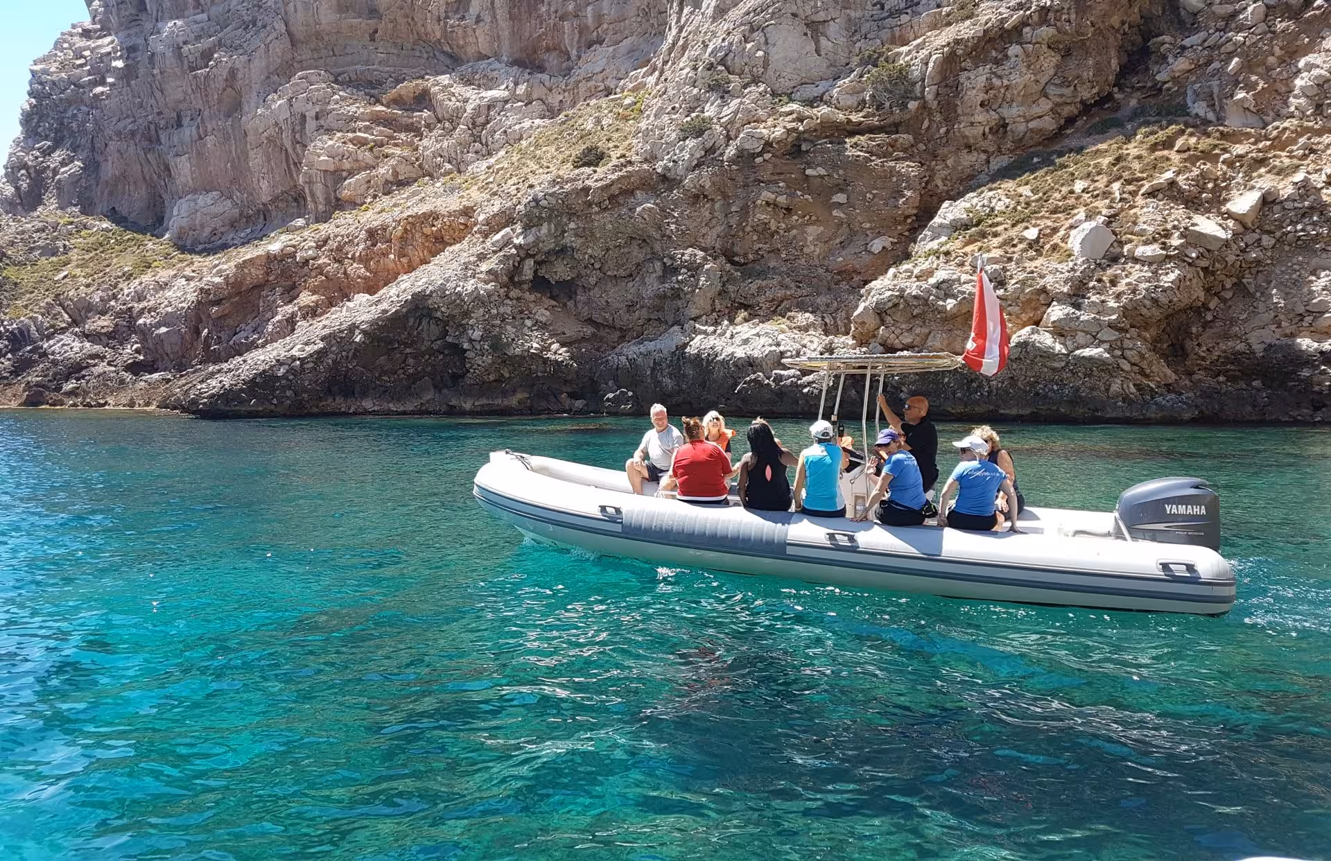 Tourists enjoying a boat ride near Capo Caccia cliffs in Alghero, exploring crystal-clear waters perfect for snorkelling.