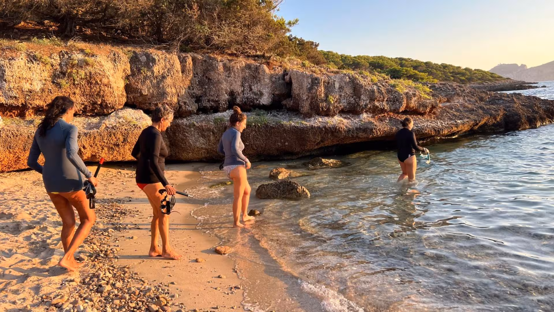 Group preparing for snorkelling on a sunny beach in Porto Conte Park, Alghero, ideal for adventure seekers.