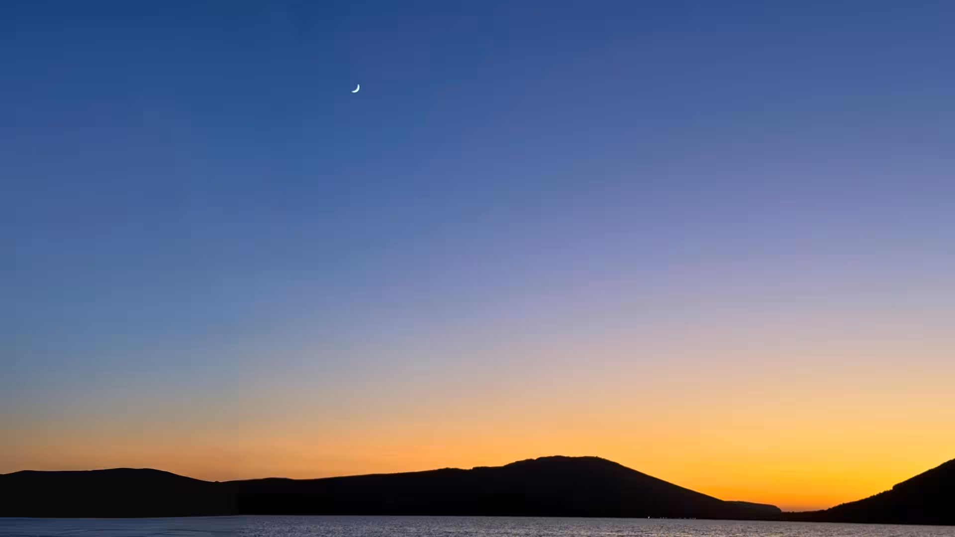 Stunning Alghero sunset with crescent moon over calm sea, perfect for a serene private dinghy tour experience.