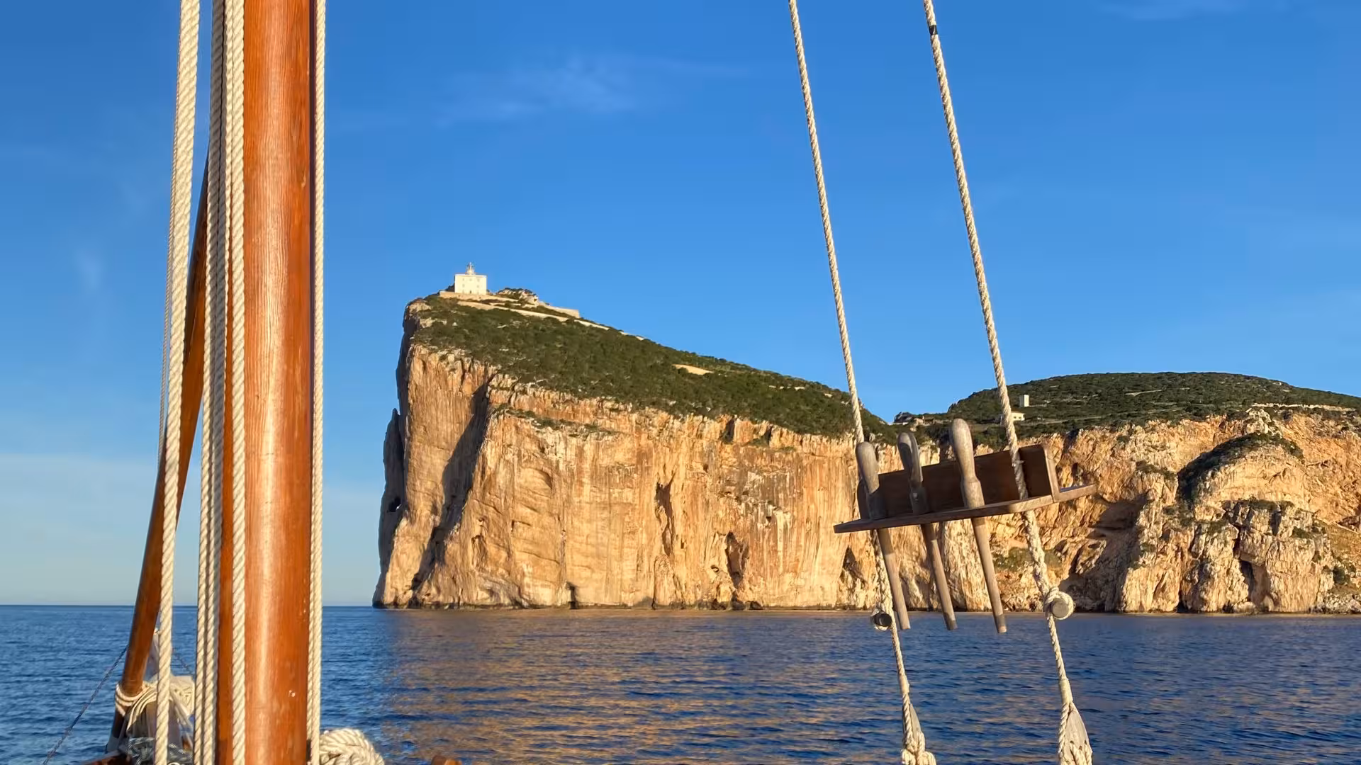 View from a sailboat of the majestic Capo Caccia cliffs during an Alghero sunset sailing tour.