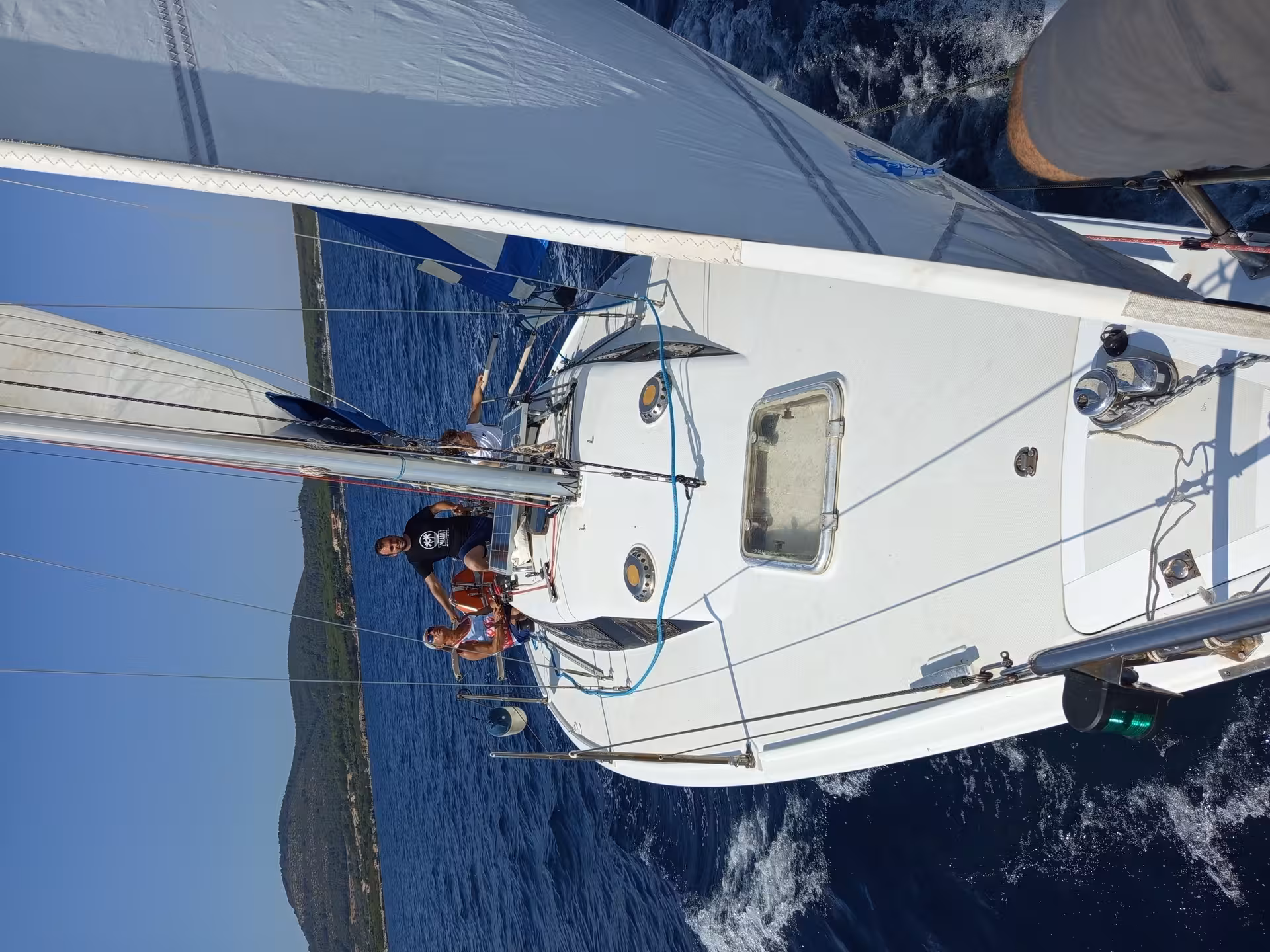 Sailboat gliding near Alghero's historic coastline during a picturesque sunset sailing tour.