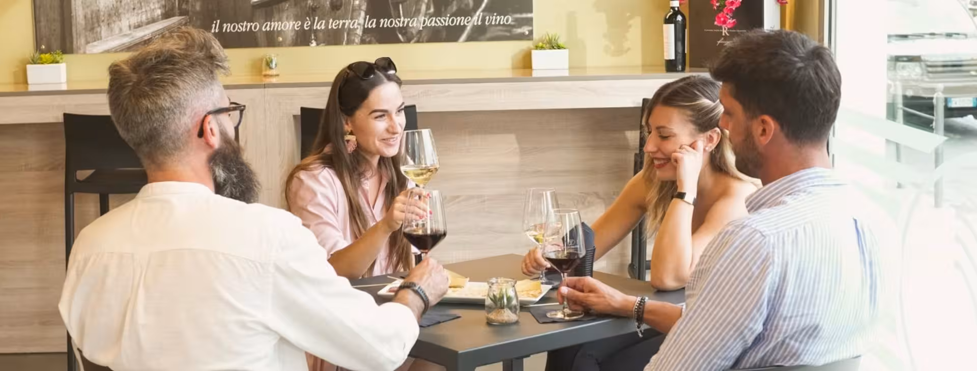 Group enjoying wine tasting in a cozy Alghero café during the historic centre tour.