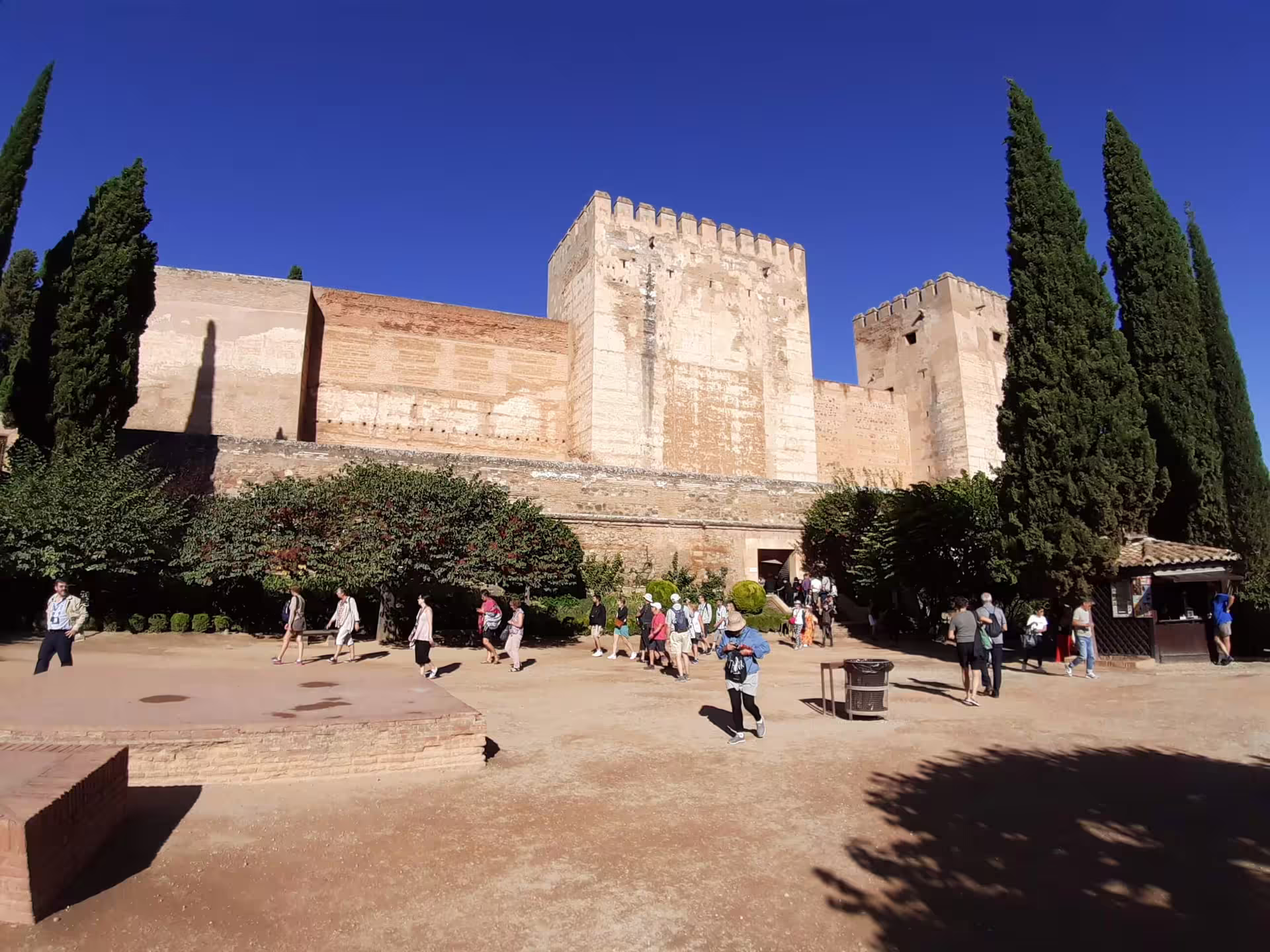Visitors enter the Alhambra fortress walls in Granada on a private walking tour under clear blue skies