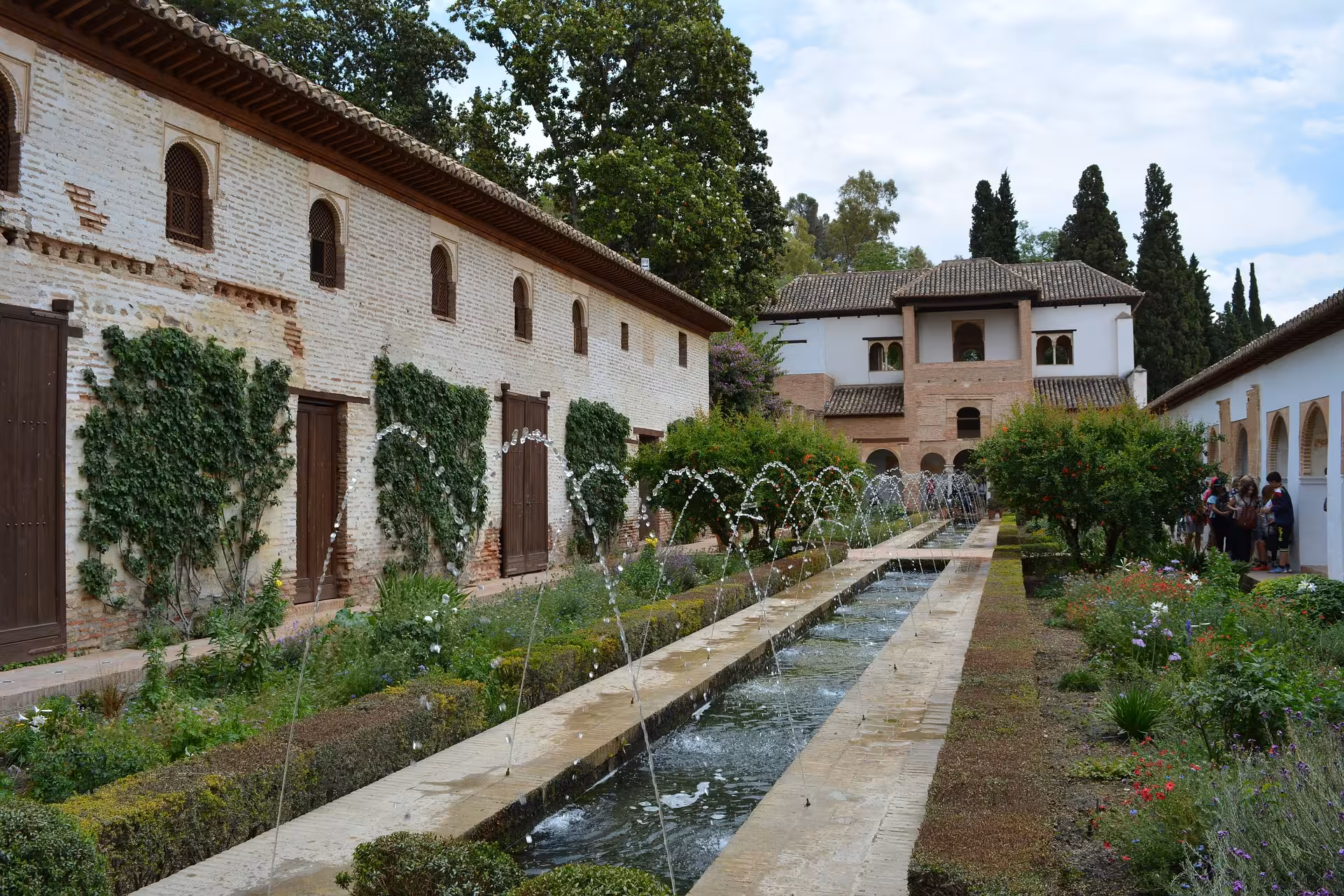 Lush gardens of the Alhambra's Generalife with vibrant flowers and elegant fountains, enhancing the serene ambiance.