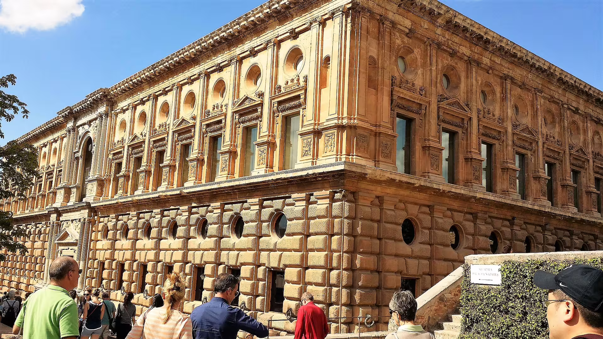 Group walking tour outside the Alhambra Palace complex in Granada, Spain, with visitors and historic facade