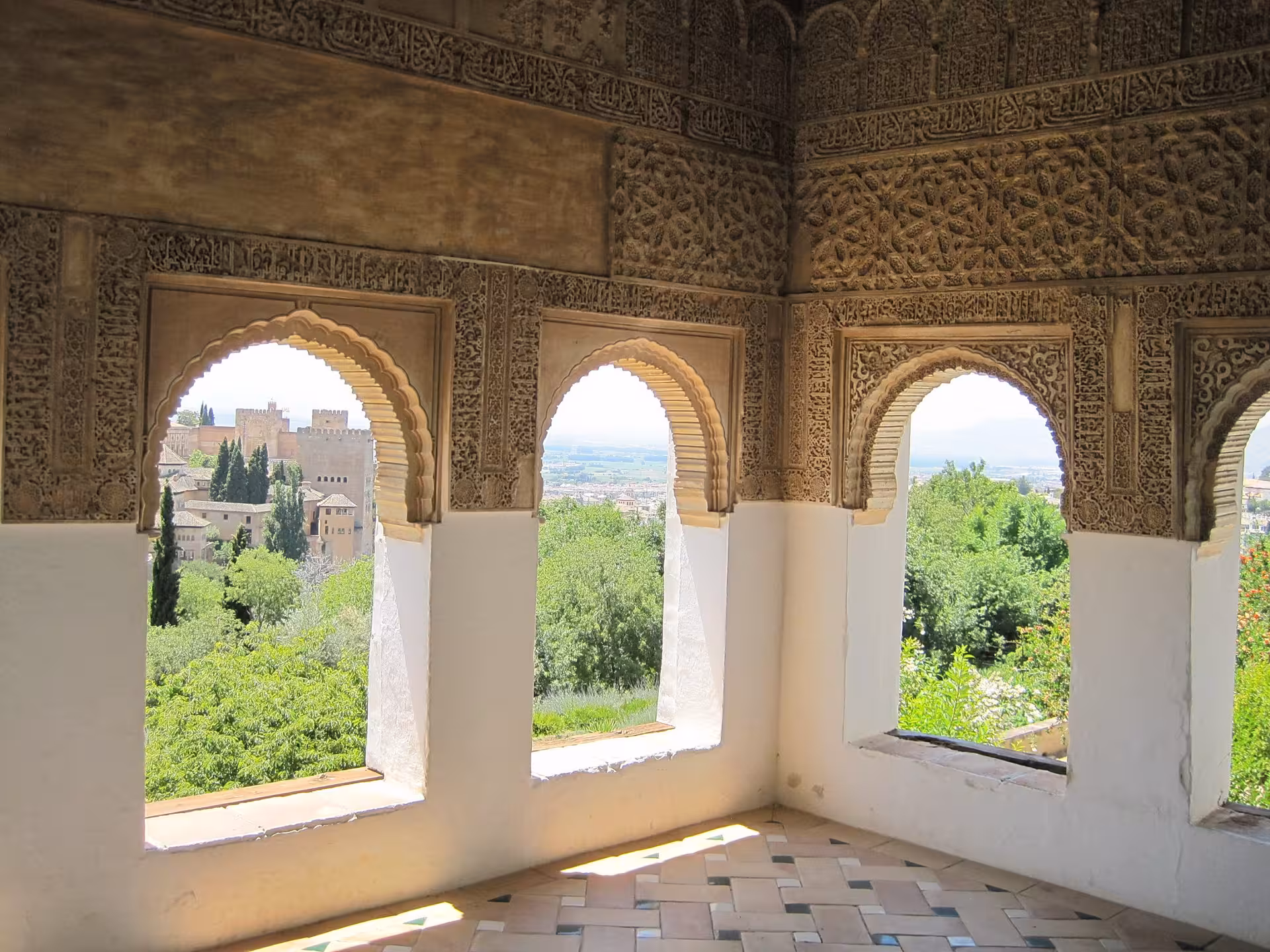 Intricate Moorish arches framing stunning views of the Alhambra from inside the palace.